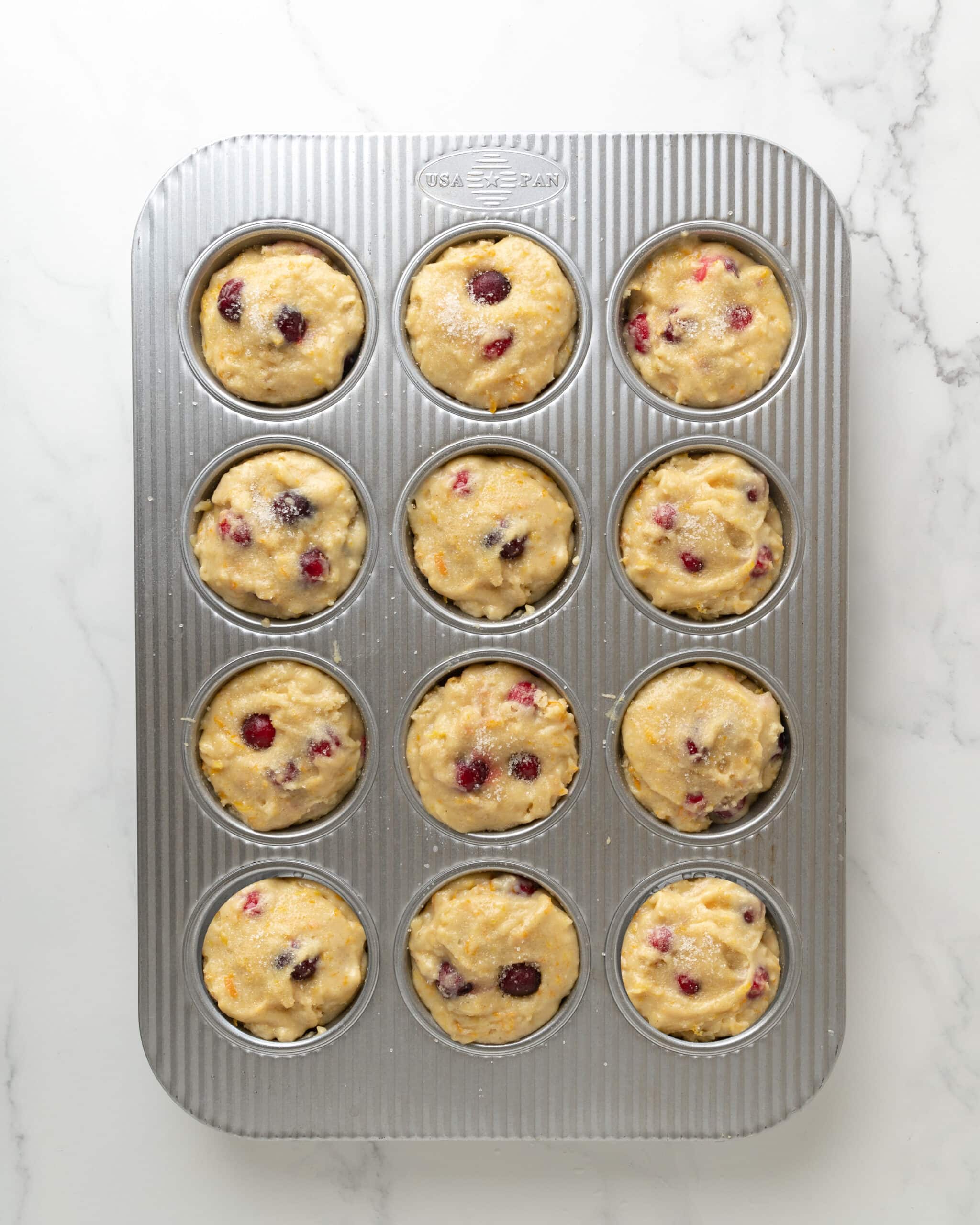 cranberry orange muffin batter in muffin tin.