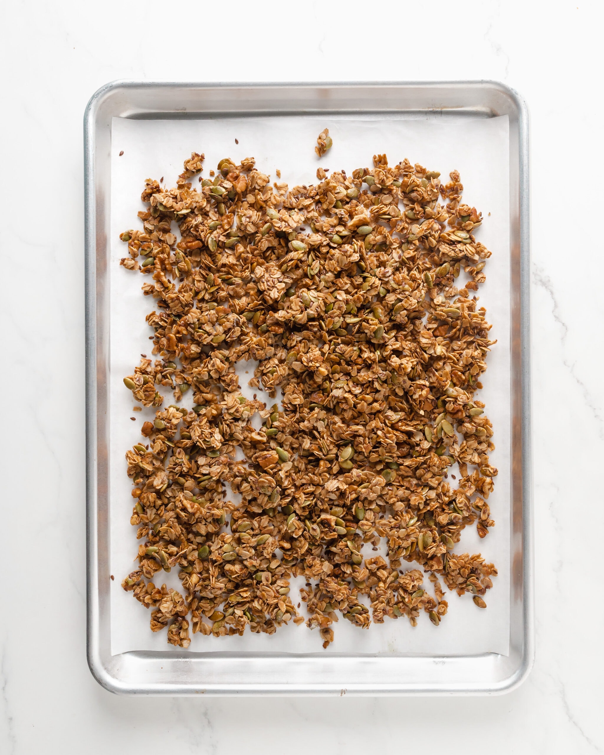 A large silver baking tray with fully baked pumpkin granola. 
