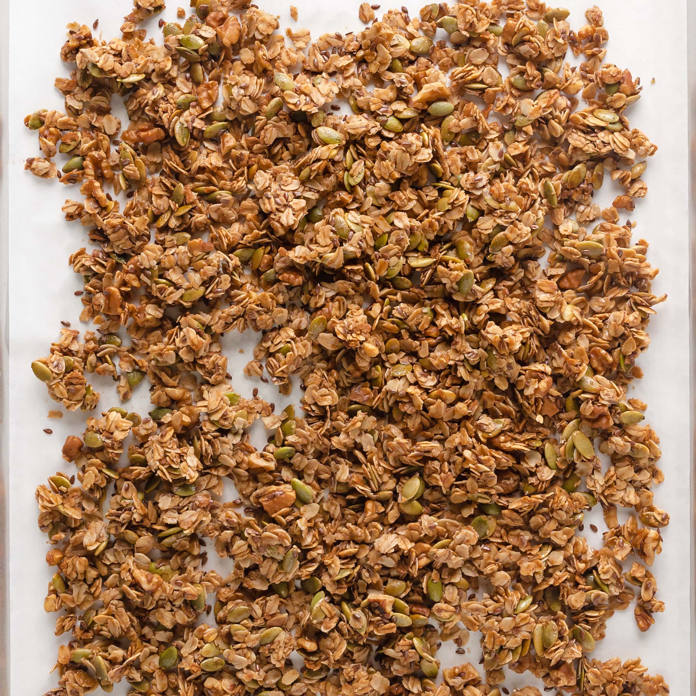 Pumpkin seed flax granola on white parchment paper.