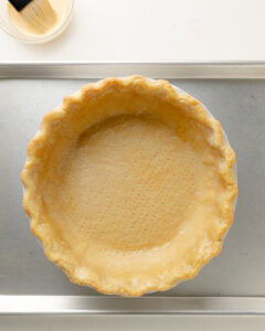 Applying egg wash to pie crust.
