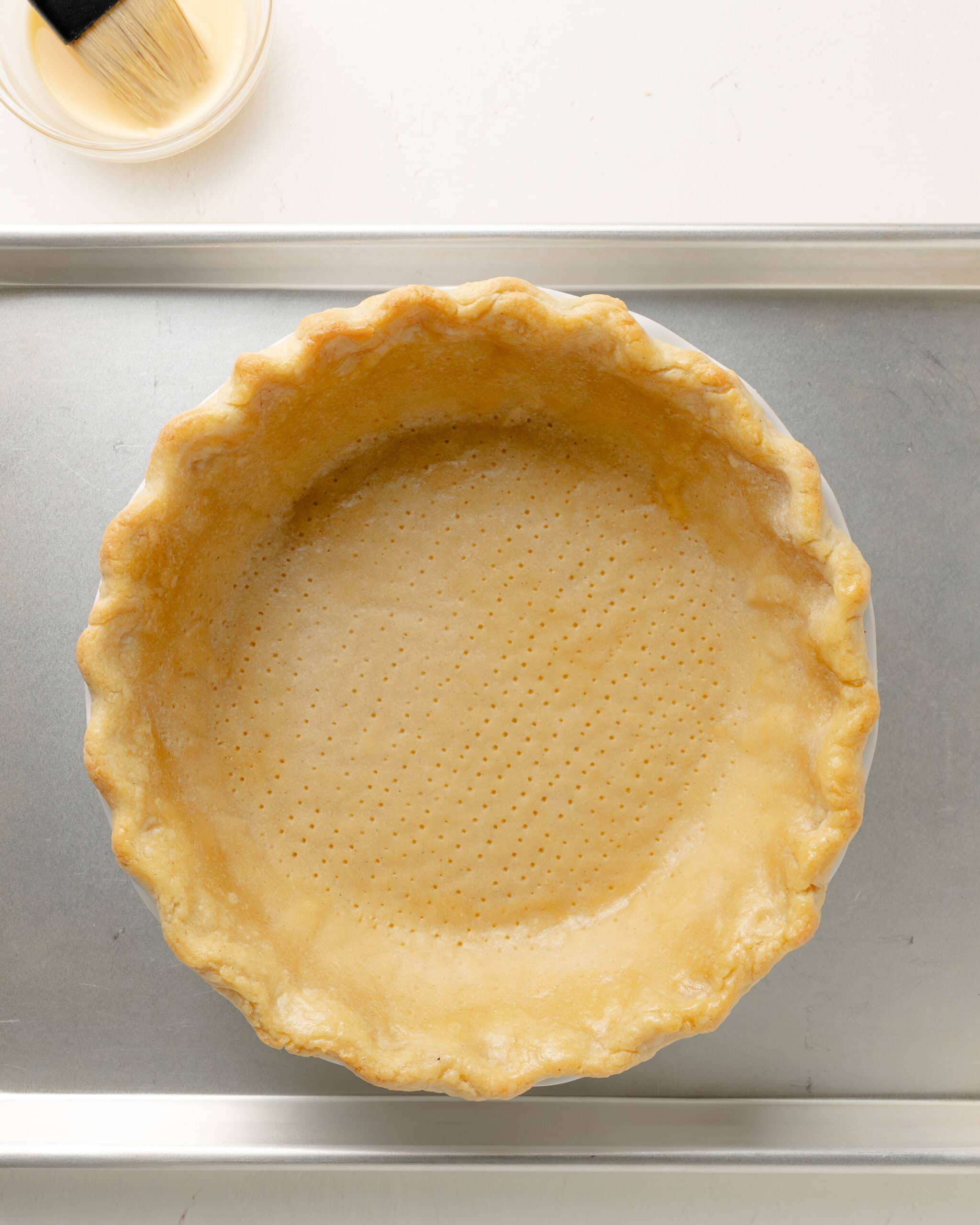 Applying egg wash to pie crust.
