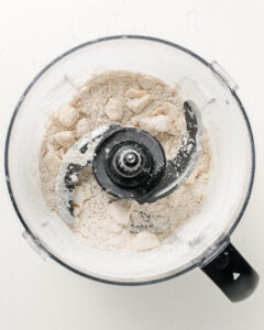 Adding the cold cubed butter to a food processor.