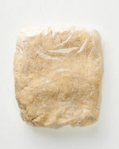 Pie dough shaped in a square and wrapped in plastic.