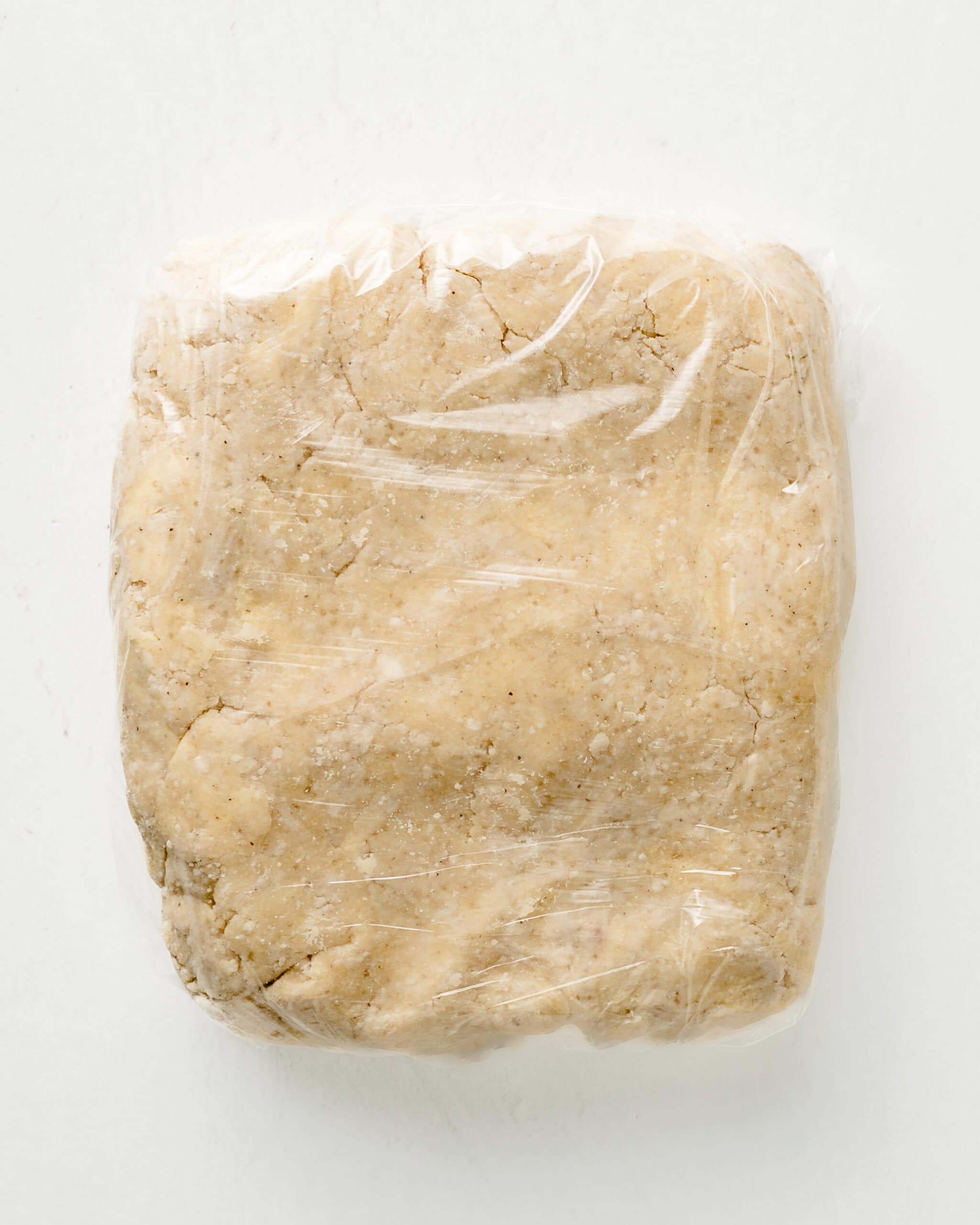 Pie dough shaped in a square and wrapped in plastic.