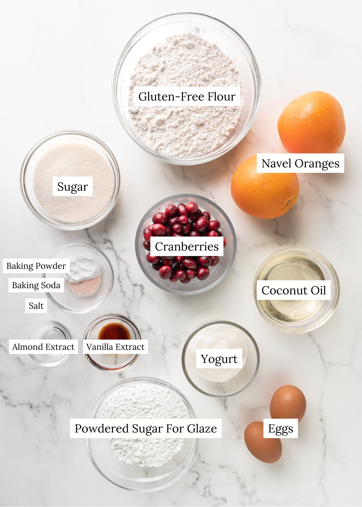 Gluten-Free cranberry orange bread ingredients. Gluten-free flour in a clear bowl with navel oranges, cranberries, leavening agents, oil yogurt, eggs, and powdered sugar. 