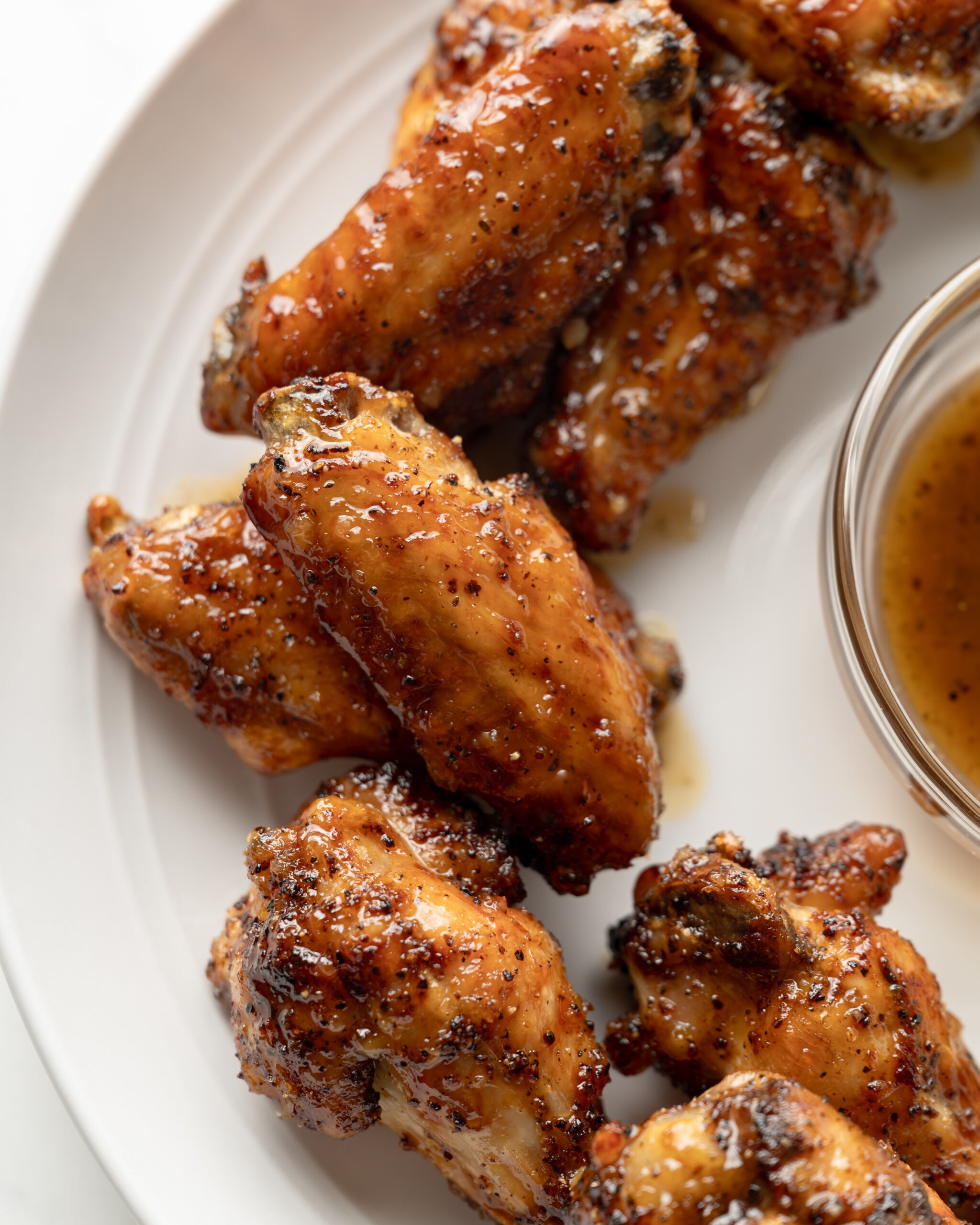 A close up of air fryer honey lemon pepper chicken wings on a white plate.