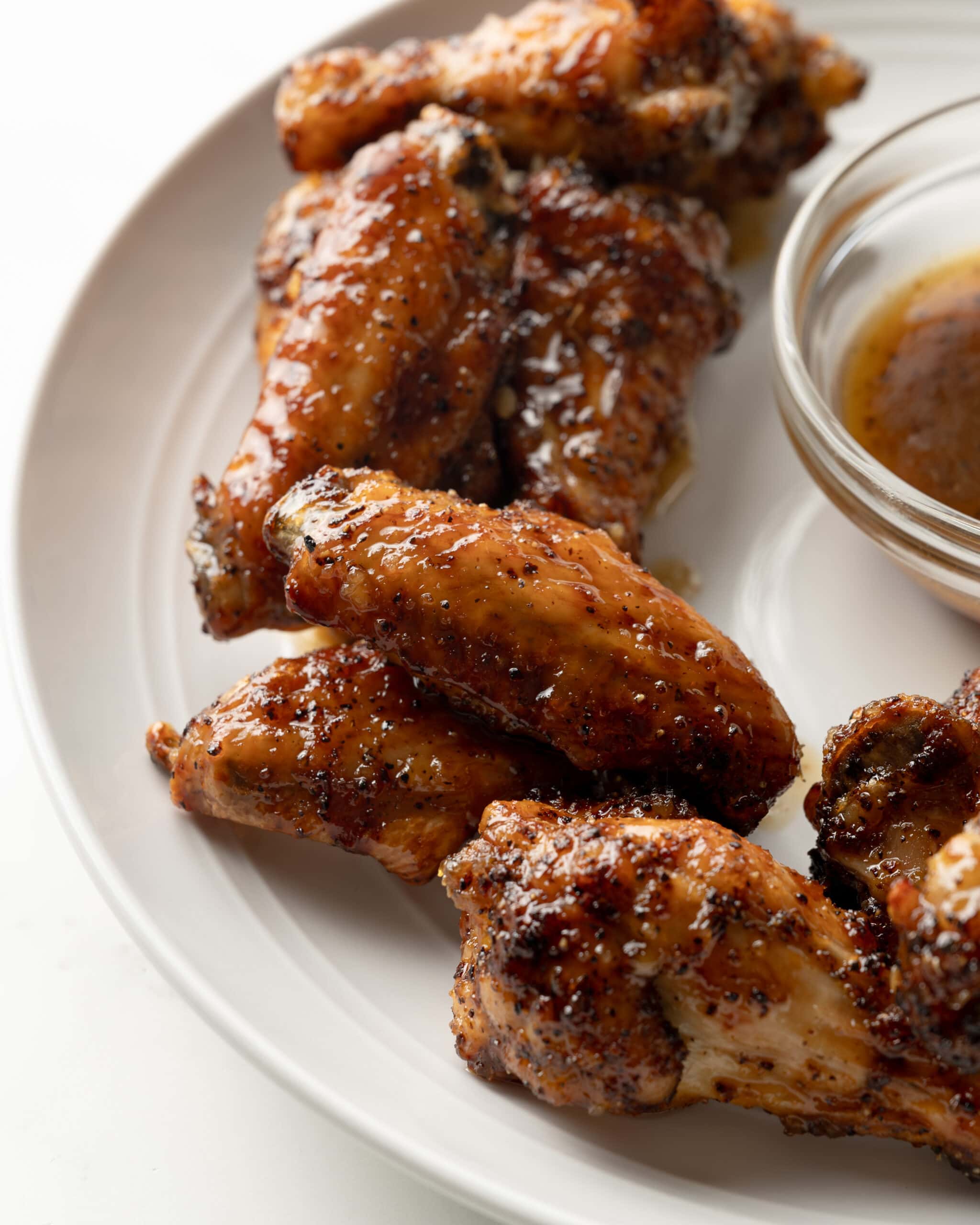 Side view of airy fryer honey lemon pepper chicken wings, with a close up on the honey glaze. 