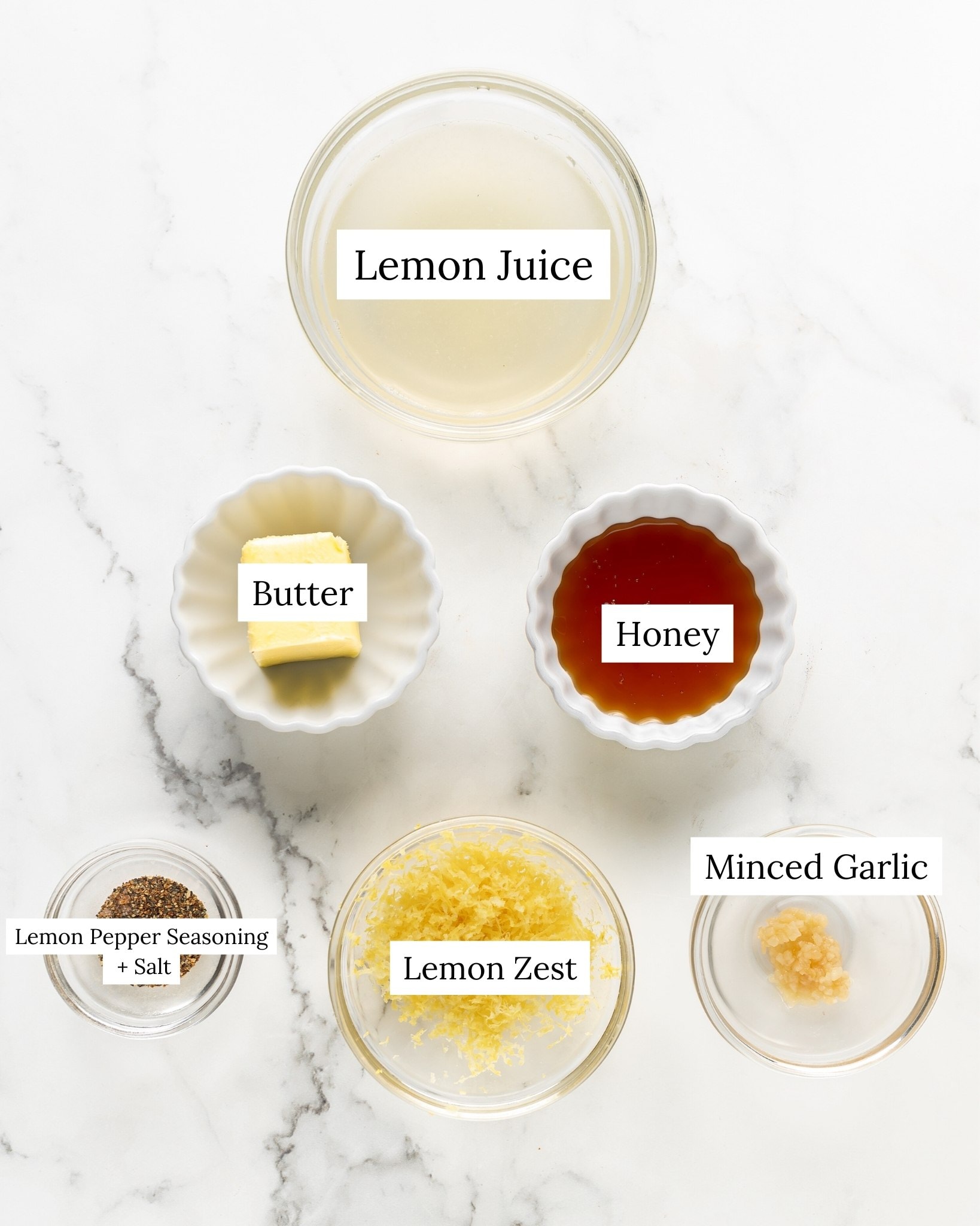 Ingredients for honey lemon pepper chicken wing glaze. Lemon juice with lemon zest, honey, lemon pepper seasoning, salt, butter, and minced garlic.