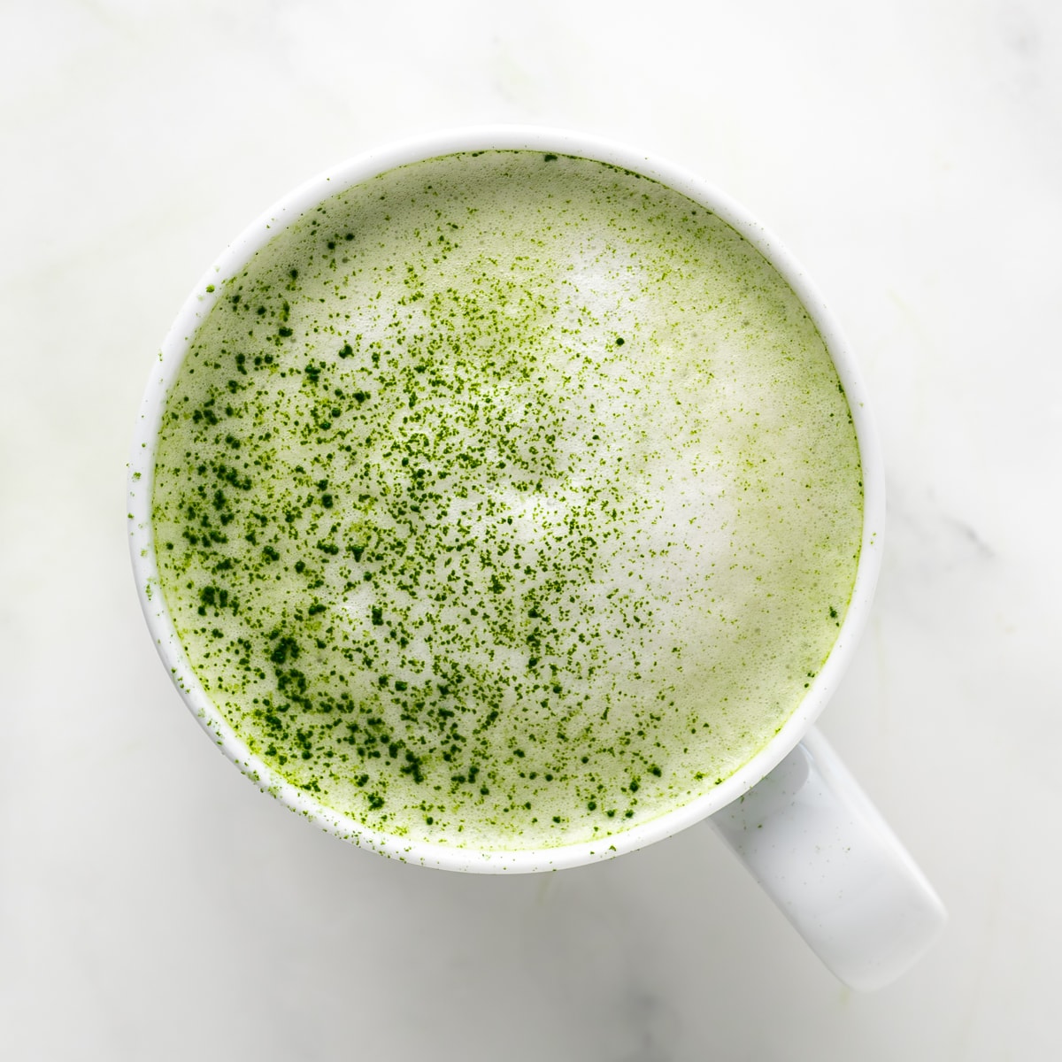 A frothed almond milk matcha latte with dusted matcha powder on top.
