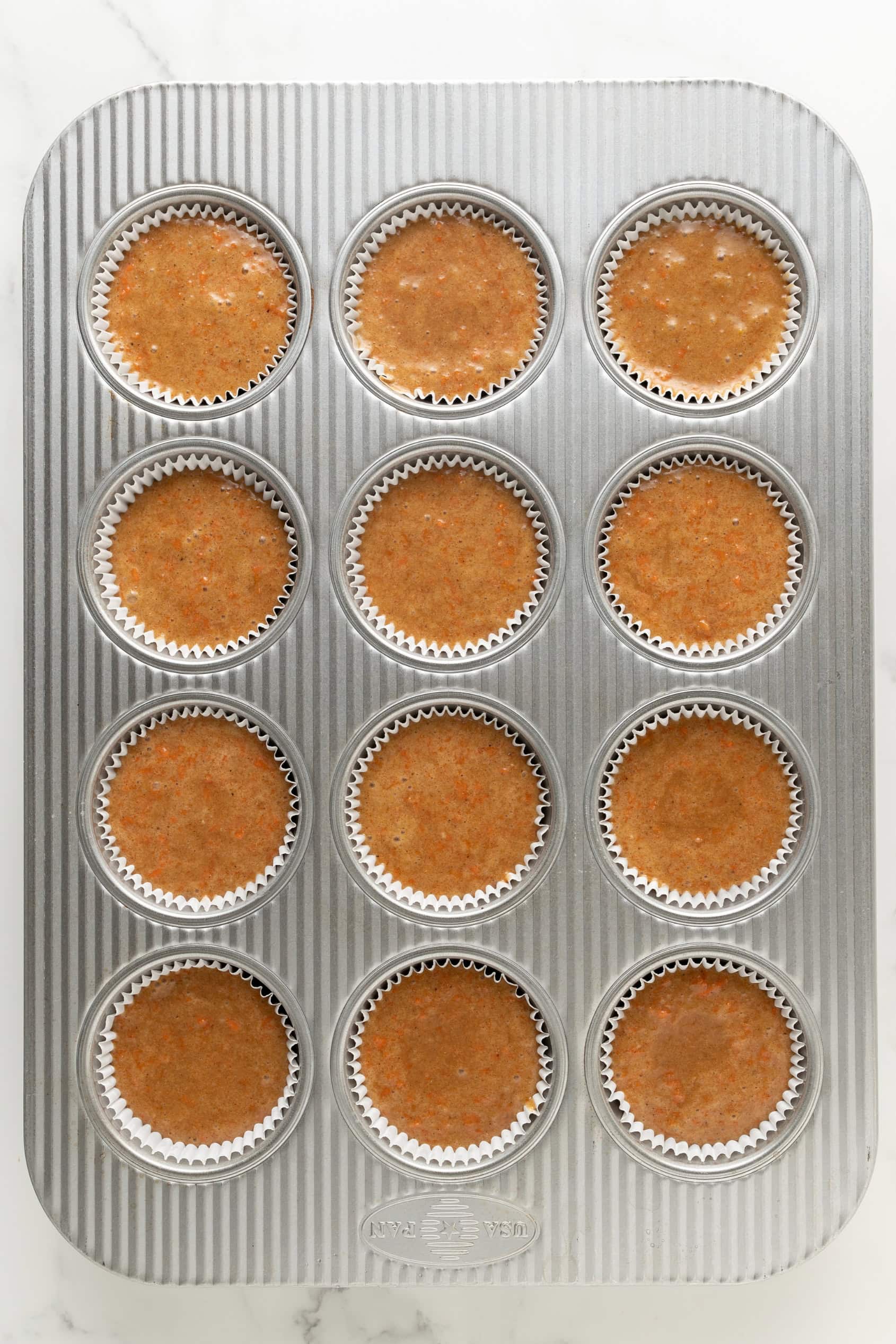 Carrot cake cupcakes divided into muffin tins.