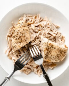 Chicken shredded in a white bowl.