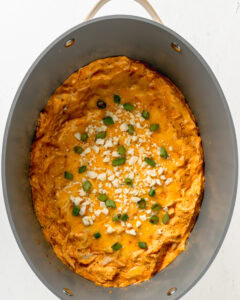 Garnish buffalo chicken dip with blue cheese and green onion.