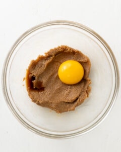 Adding an egg yolk to creamed butter and sugar.