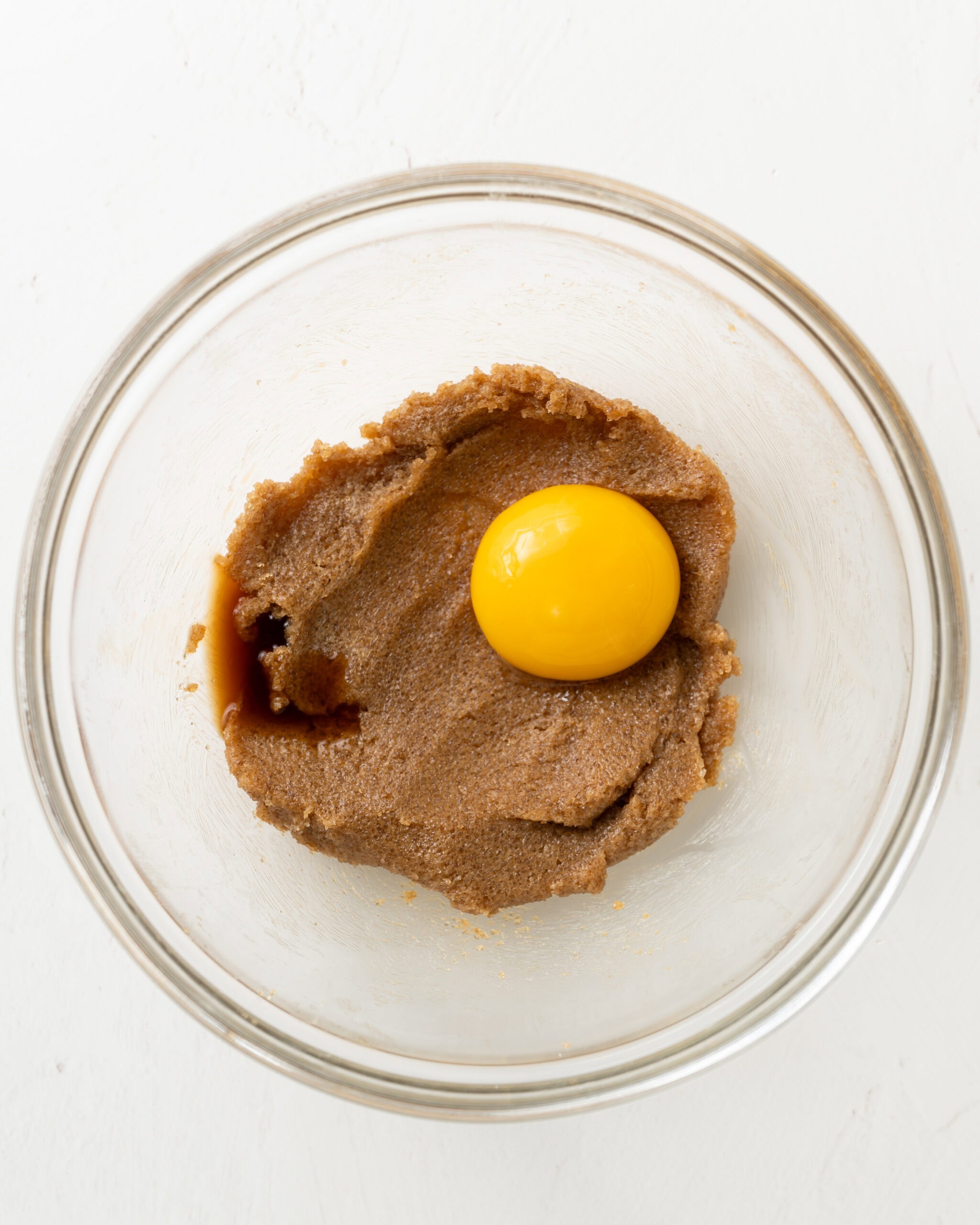 Adding an egg yolk to creamed butter and sugar.