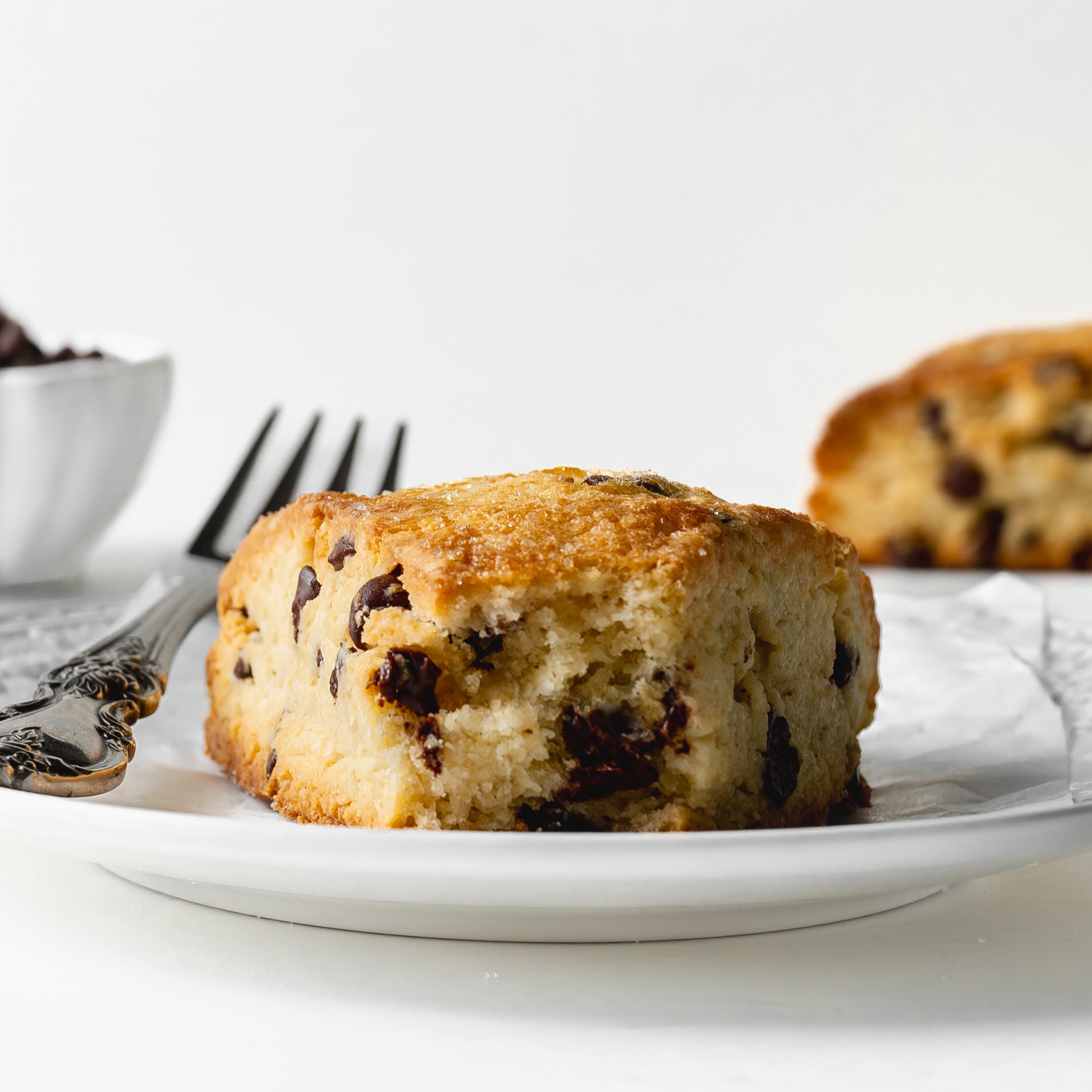 Chocolate chip scone ona. white plate with the center exposed showing the melted chocolate chips.