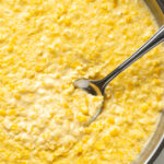 Creamed corn in a skillet with a spoon.