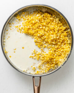 Creamed corn with milk and cream added to the skillet.