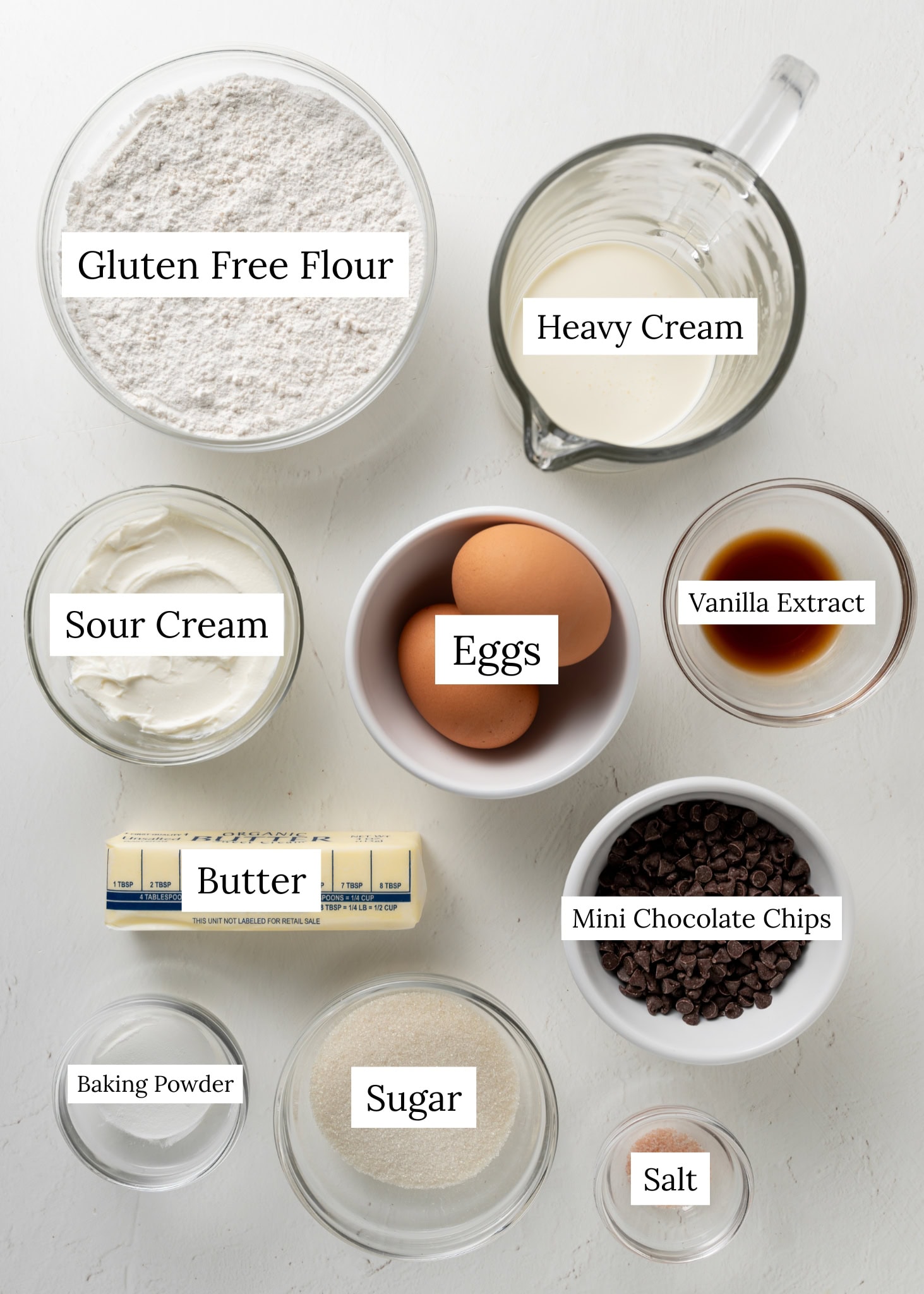 Chocolate Chip Scone Ingredients. Gluten Free Flour, Heavy Cream, Sour Cream, Eggs, Vanilla extract, Butter, Baking Powder, Salt, Sugar, and Mini Chocolate Chips.