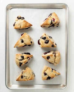 Baked blueberry scones on a lined baking sheet.