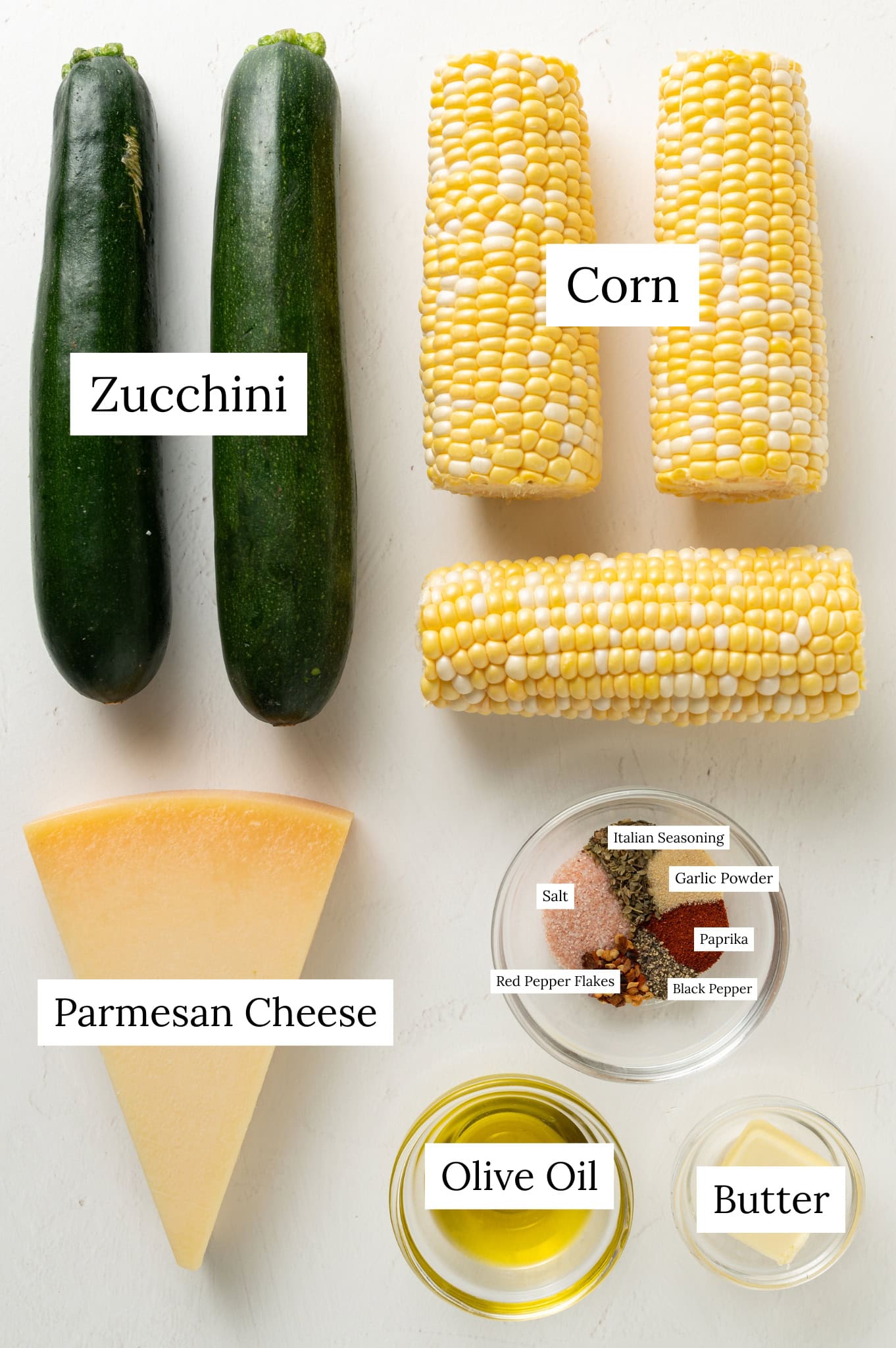 Ingredients for sauteed zucchini and corn, which includes: zucchini, 3 corn on the cobs, spices, butter, oil, and parmesan cheese.