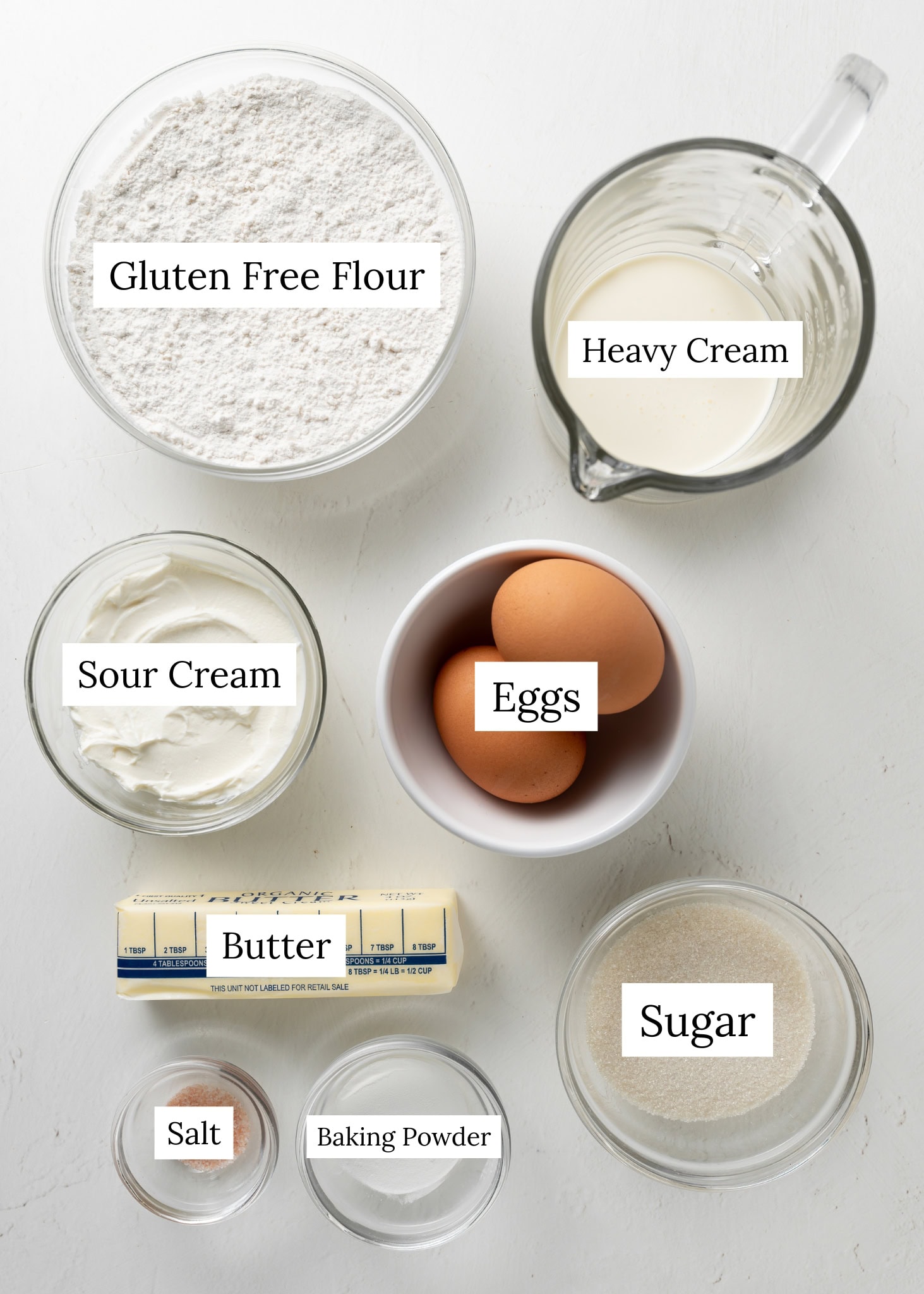 Ingredients for gluten free scones. Gluten free flour, heavy cream, sour cream, eggs, sugar, butter, salt, and baking powder.
