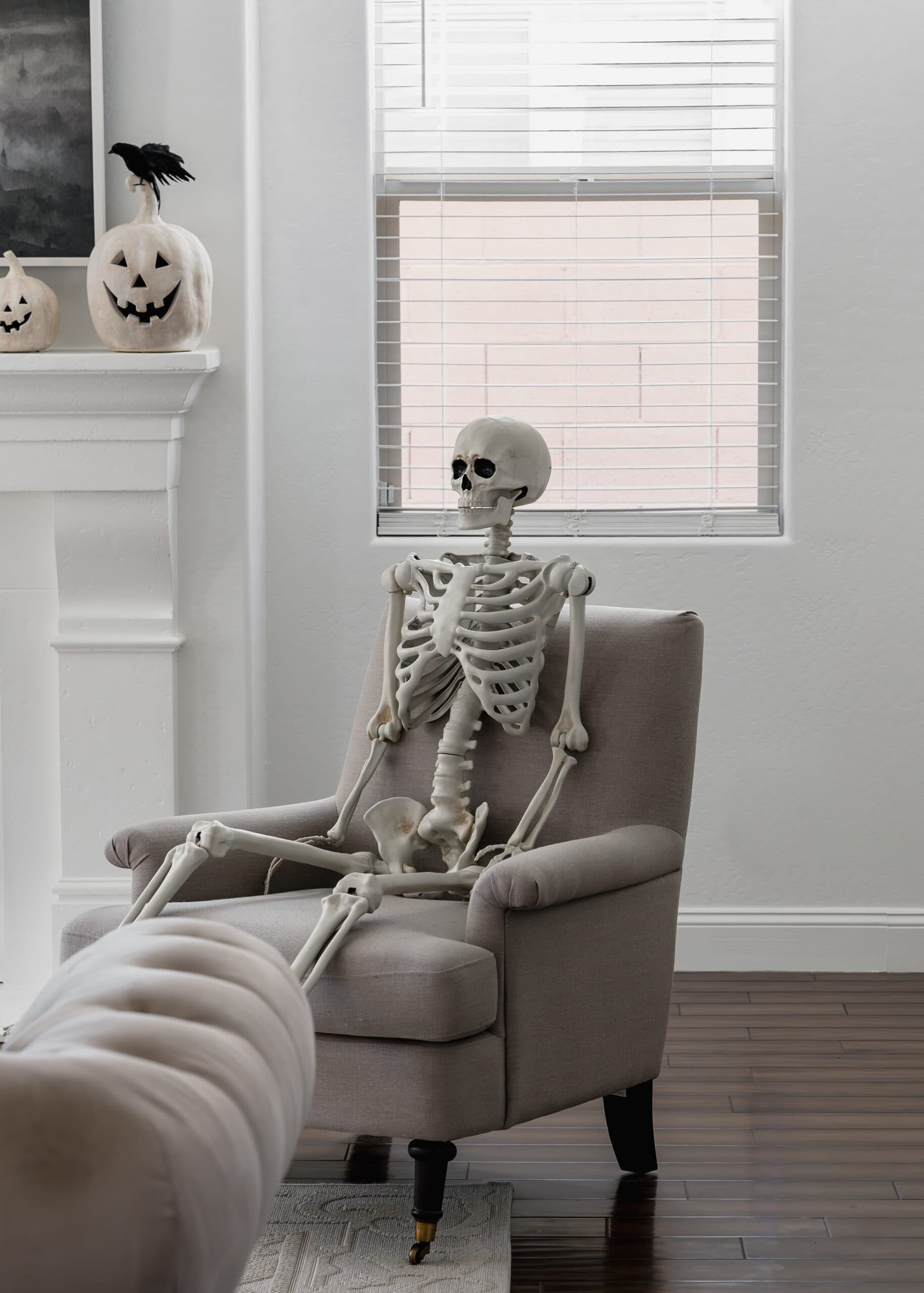 Life-sized skeleton sitting in a gray chair.