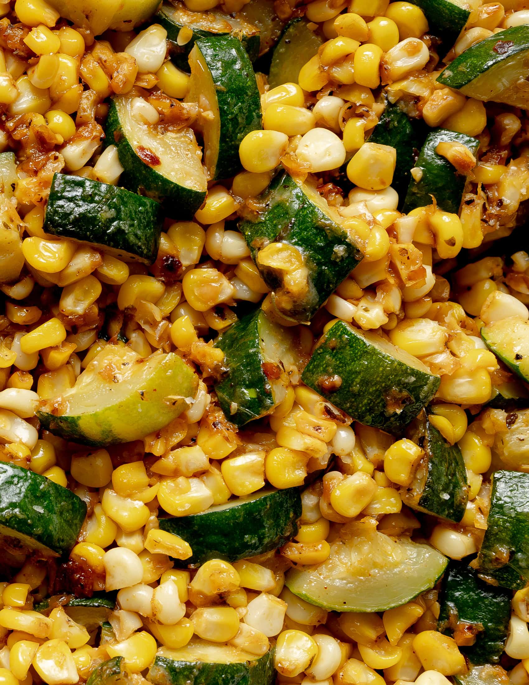 Corn and Zucchini close up with melted cheese and spices.