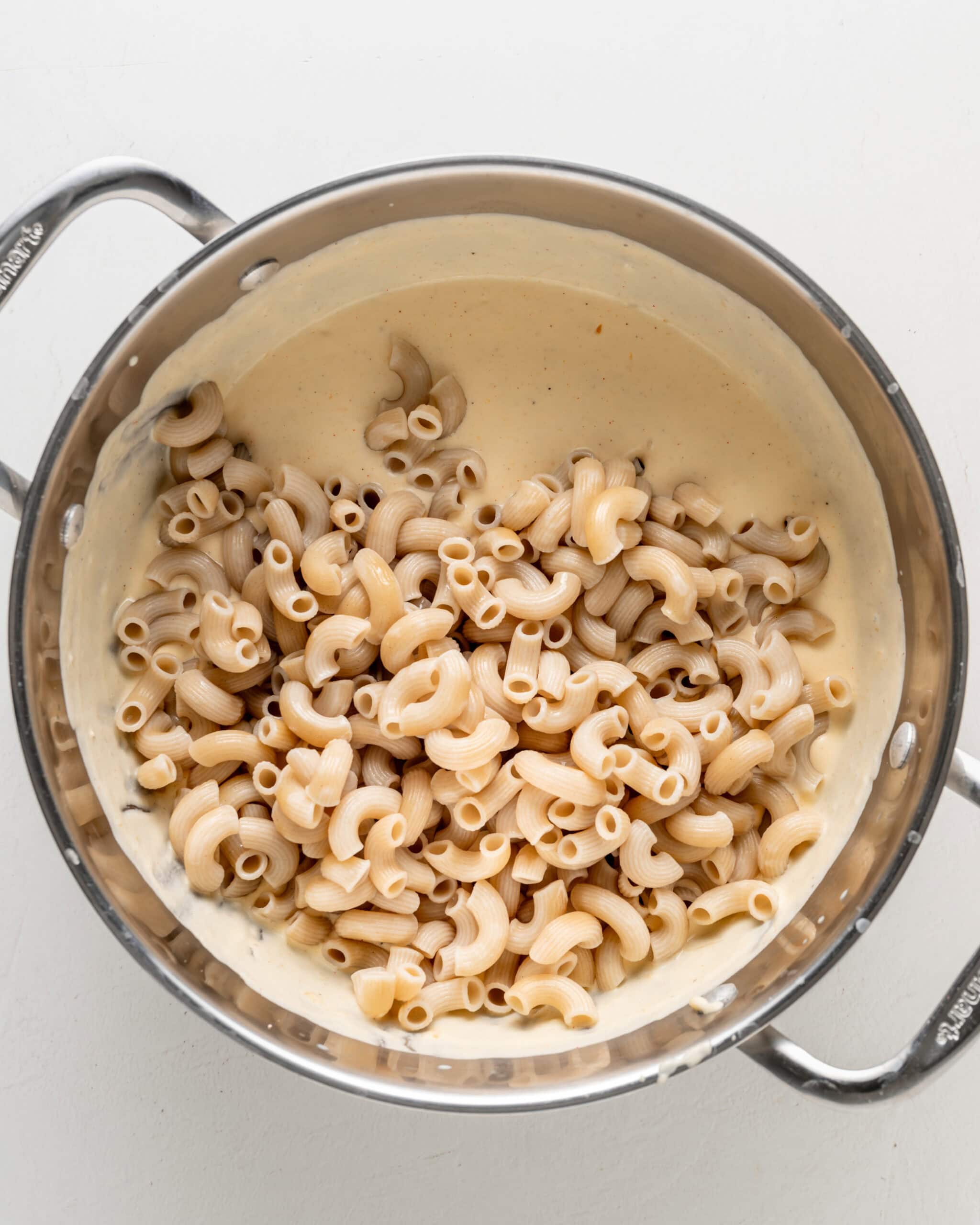 Adding noodles to mac and cheese sauce.