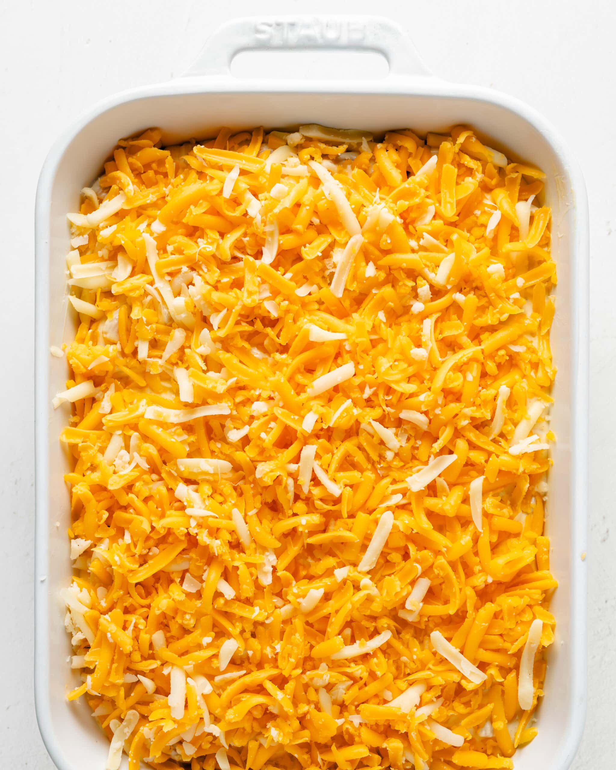 Adding cheese on top of baked mac and cheese.
