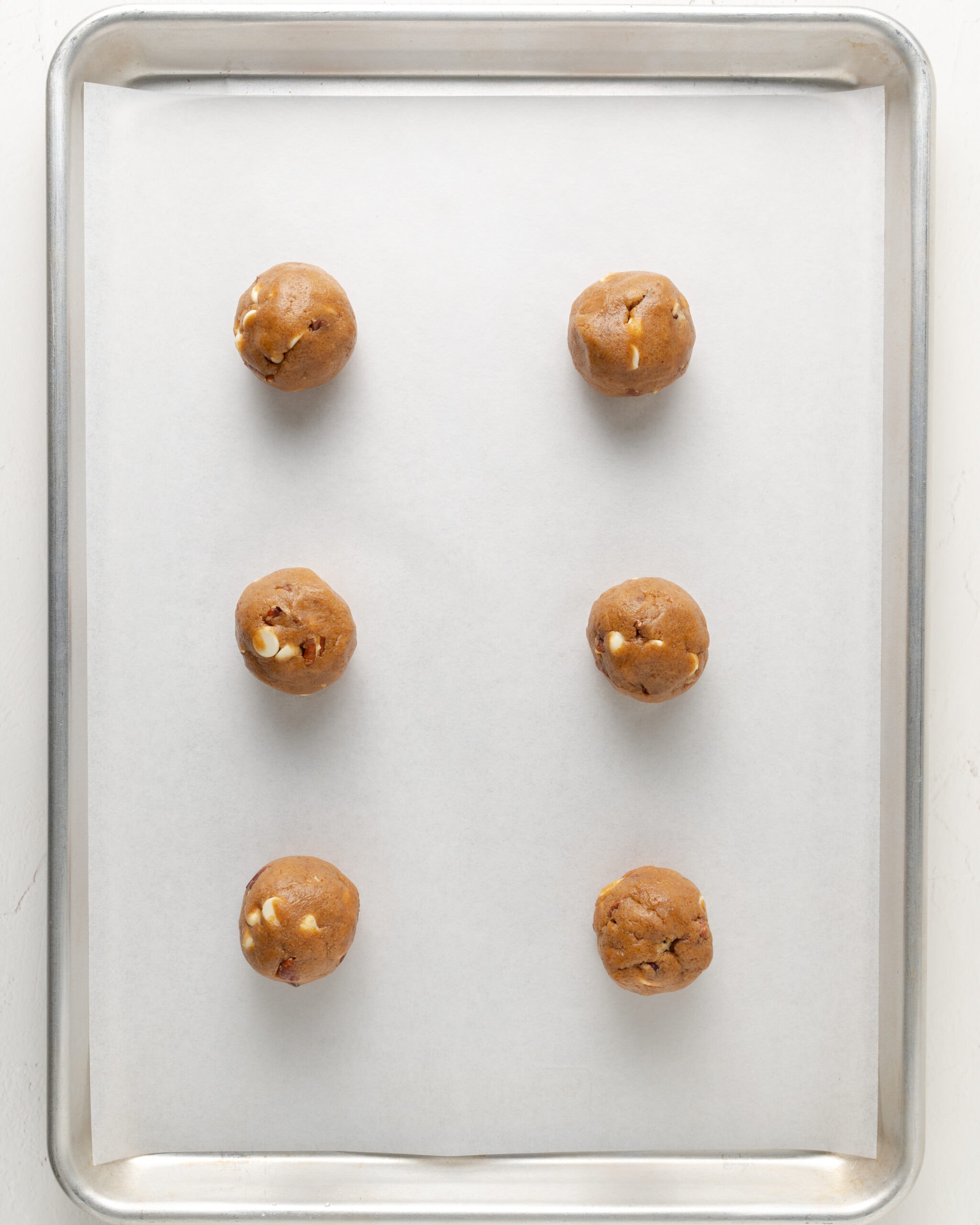 White chocolate pecan pumpkin cookie dough balls on a baking sheet.