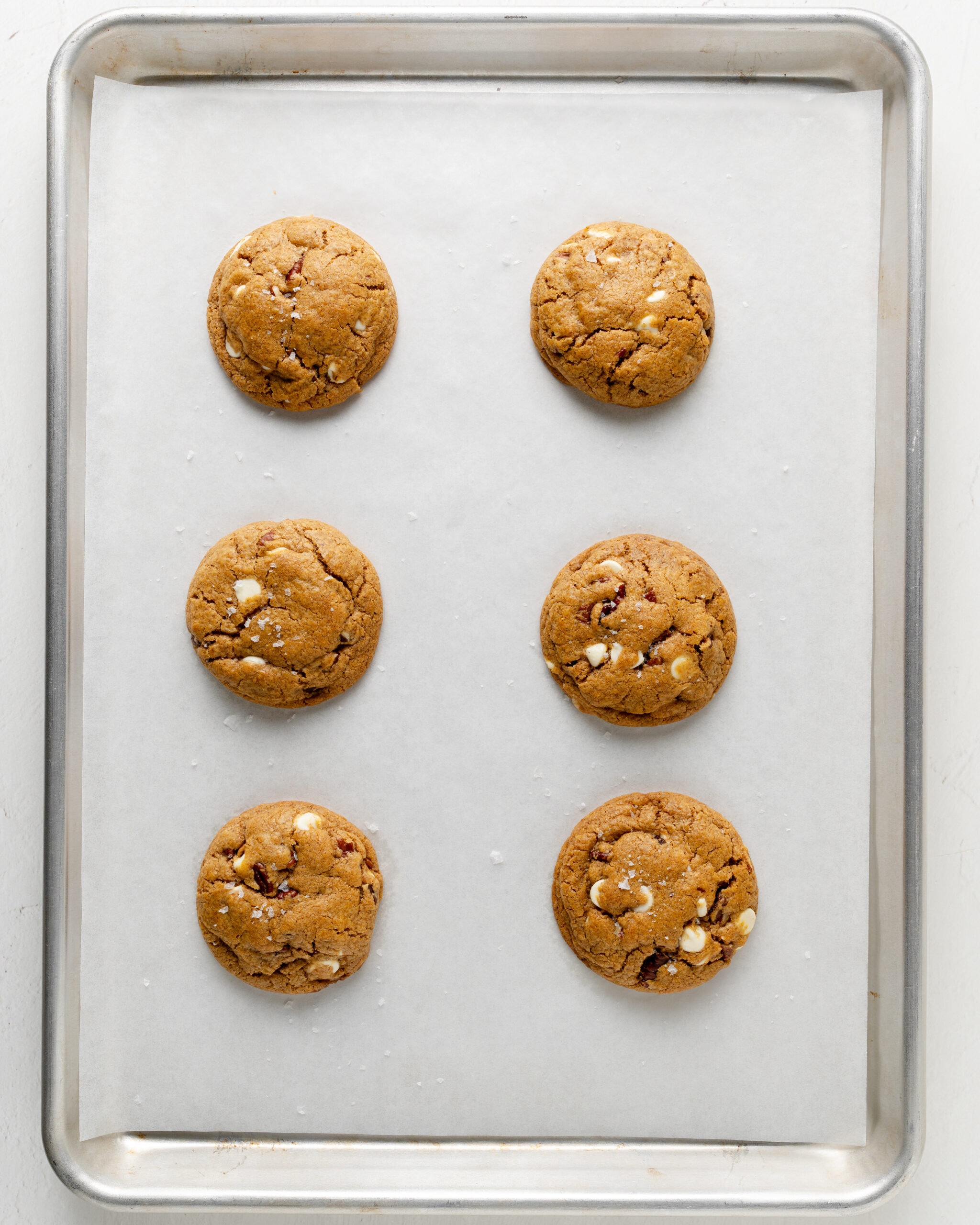 White chocolate pumpkin pecan cookies baked on a tray with parchment paper.