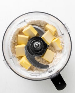 Adding butter to food processor with cornmeal dry ingredients.