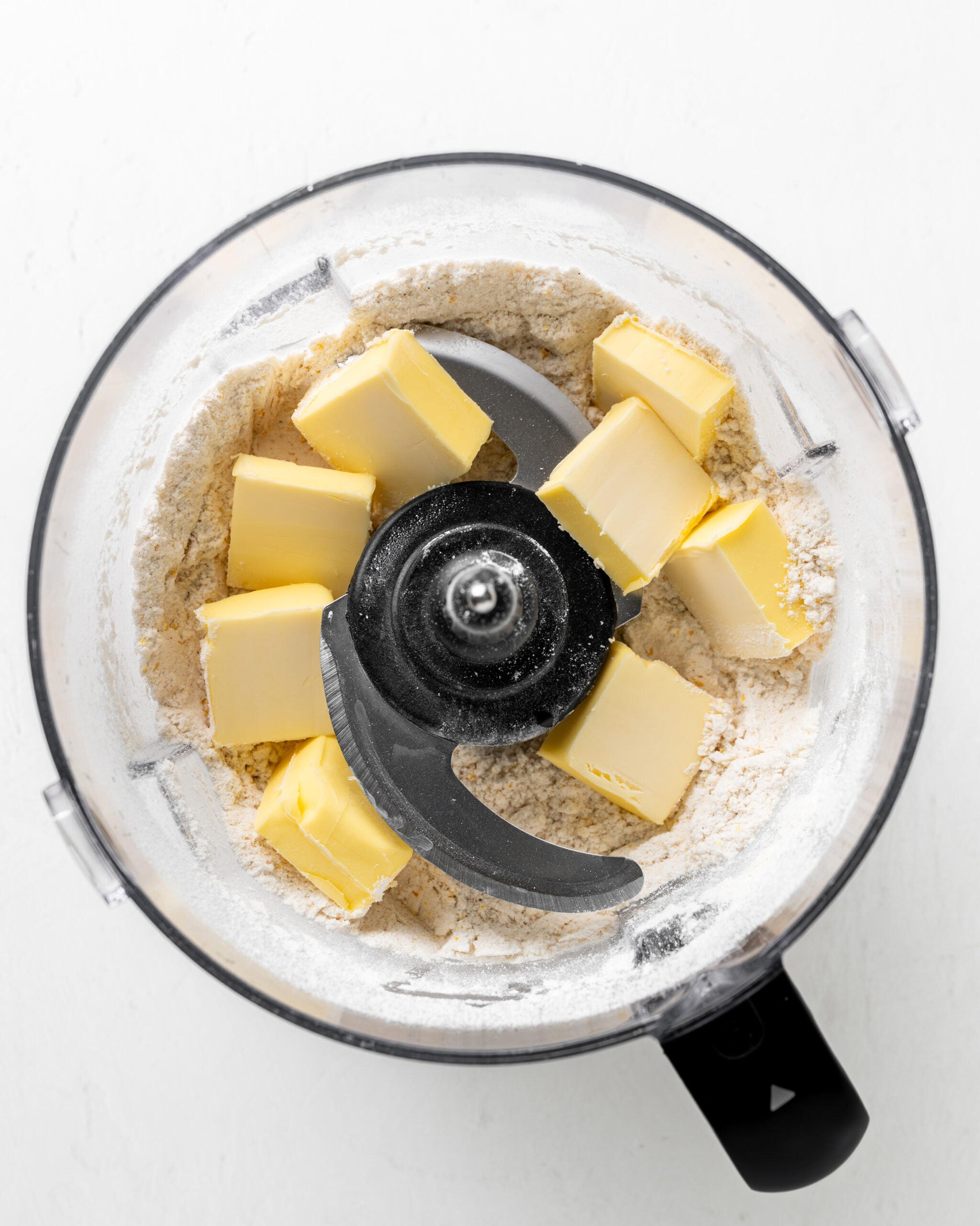 Adding butter to food processor with cornmeal dry ingredients.