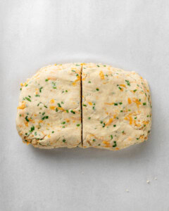 Shape the cheddar and chive scone dough into a rectangle then cut in half.
