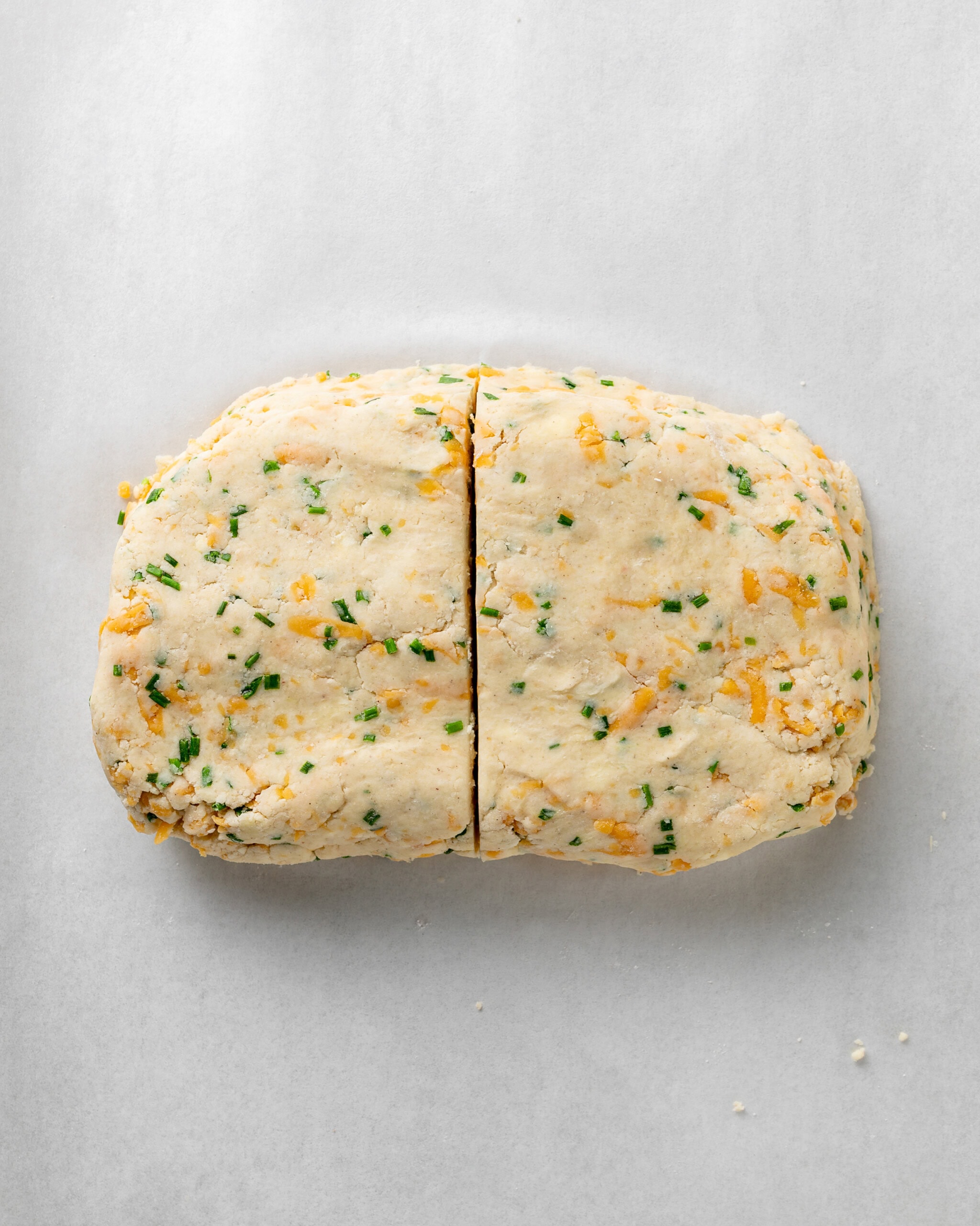 Shape the cheddar and chive scone dough into a rectangle then cut in half.