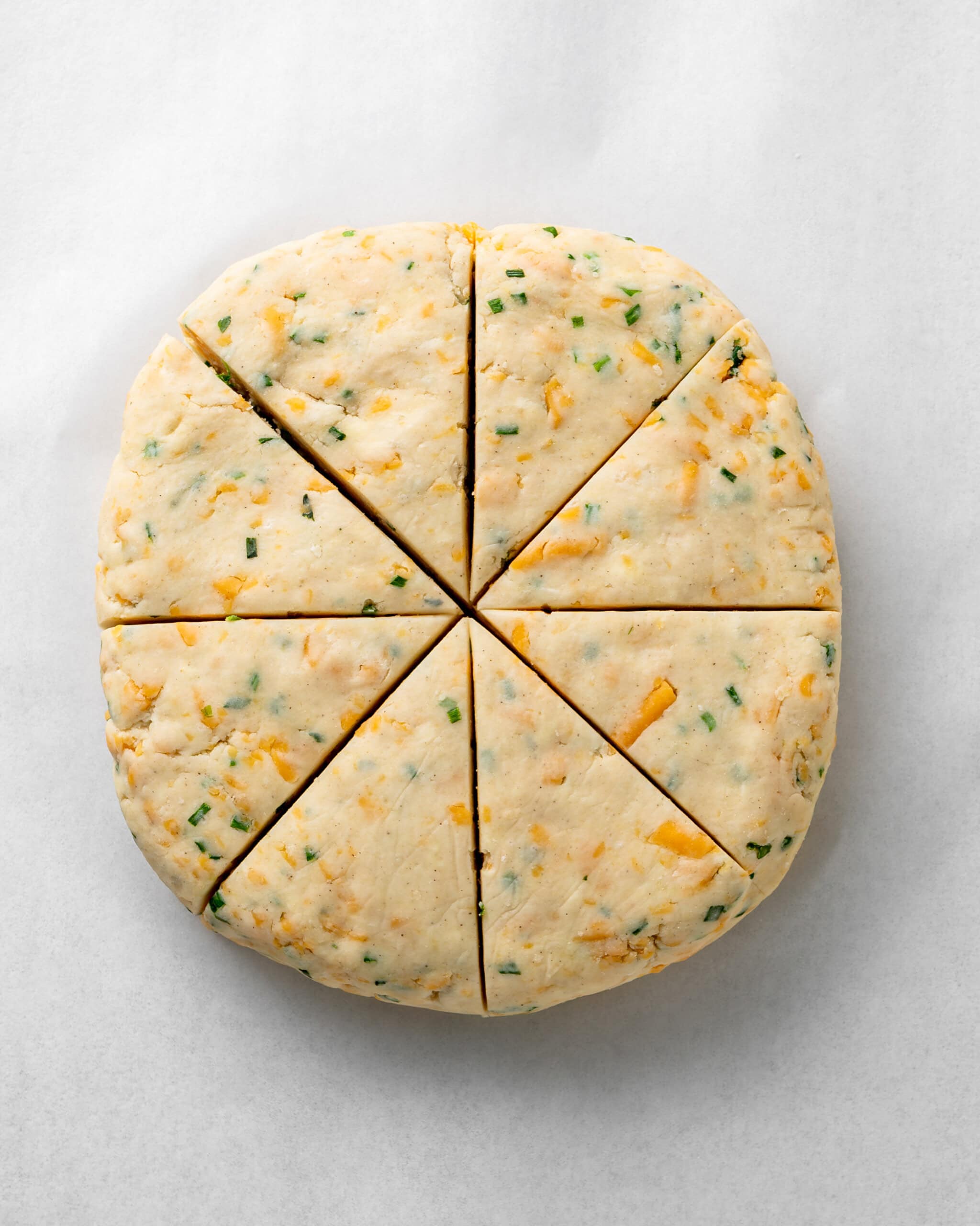 Cheddar and chive dough cut into 8 triangles.