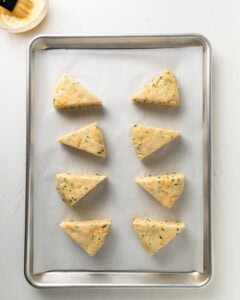 Egg wash the cheddar and chive scones before baking.