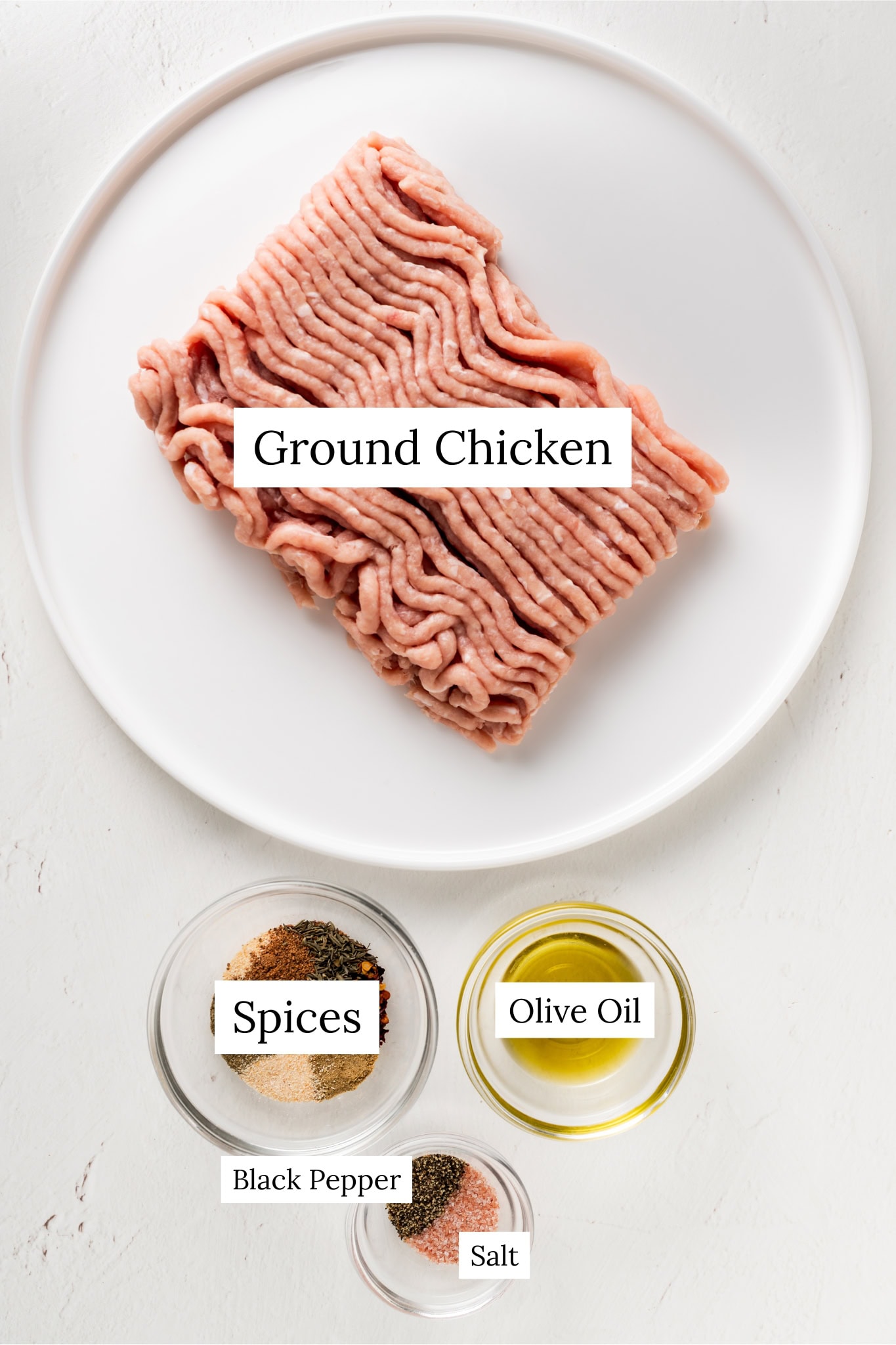 Ground chicken, a bowl of spices, and olive oil for ground chicken breakfast patties.