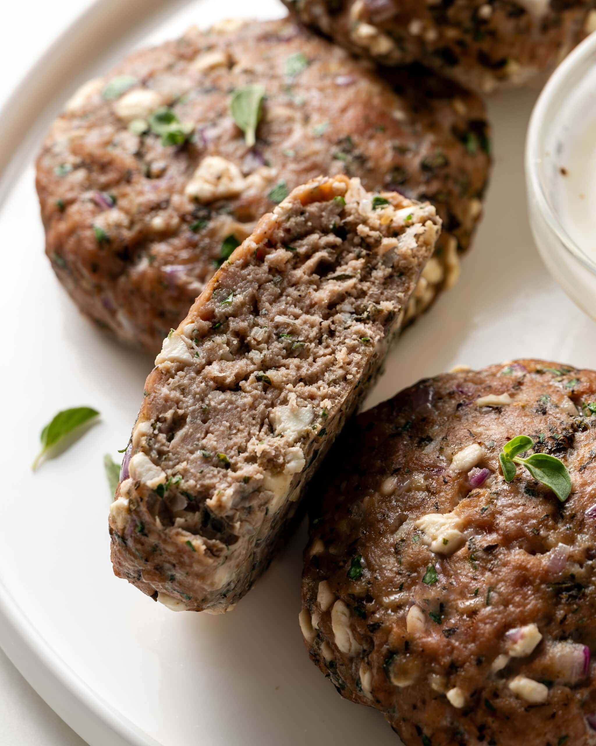 A mediterranean turkey burger cut in half to show inside feta and herbs.