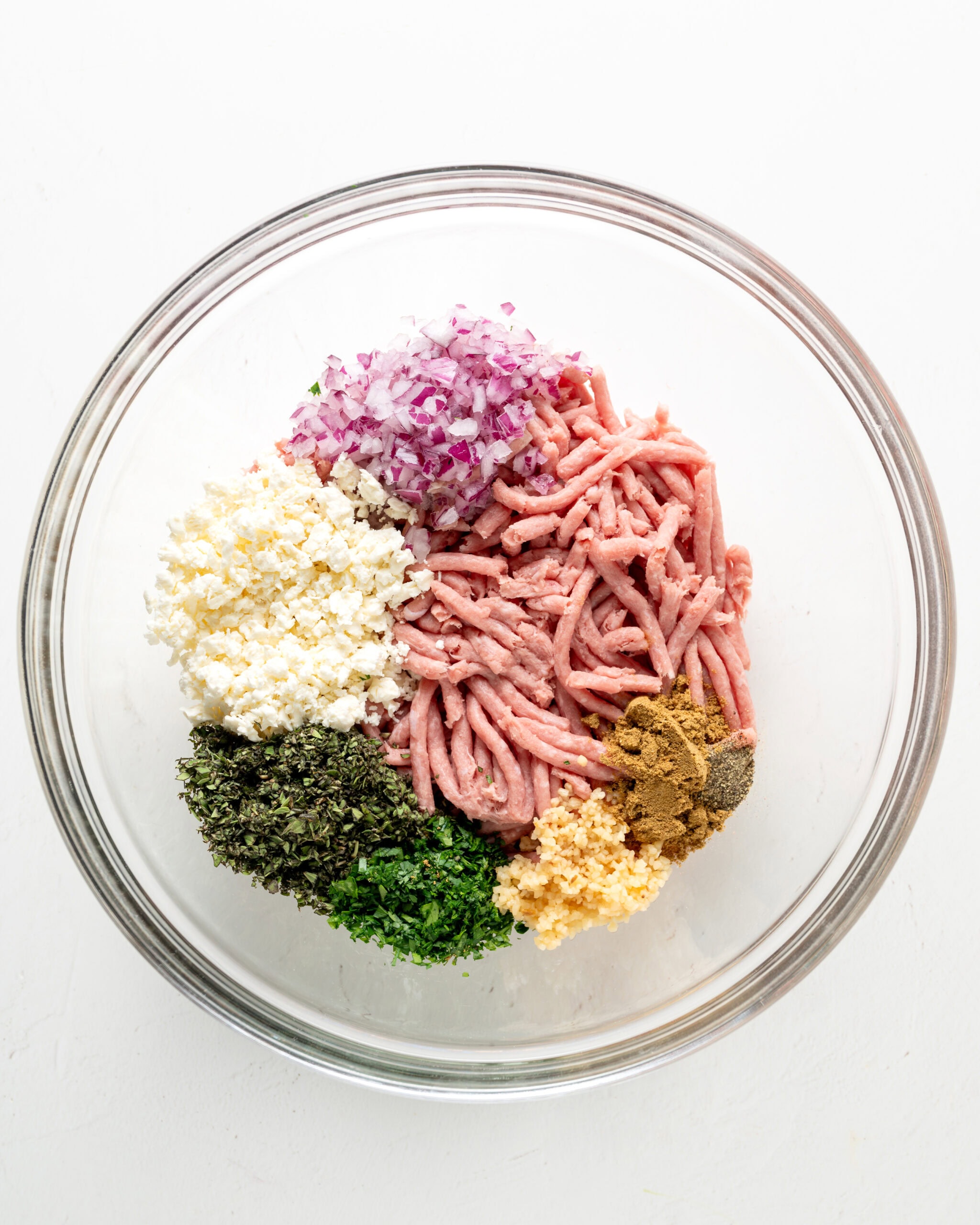 Mediterranean turkey burger ingredients in a large clear bowl.
