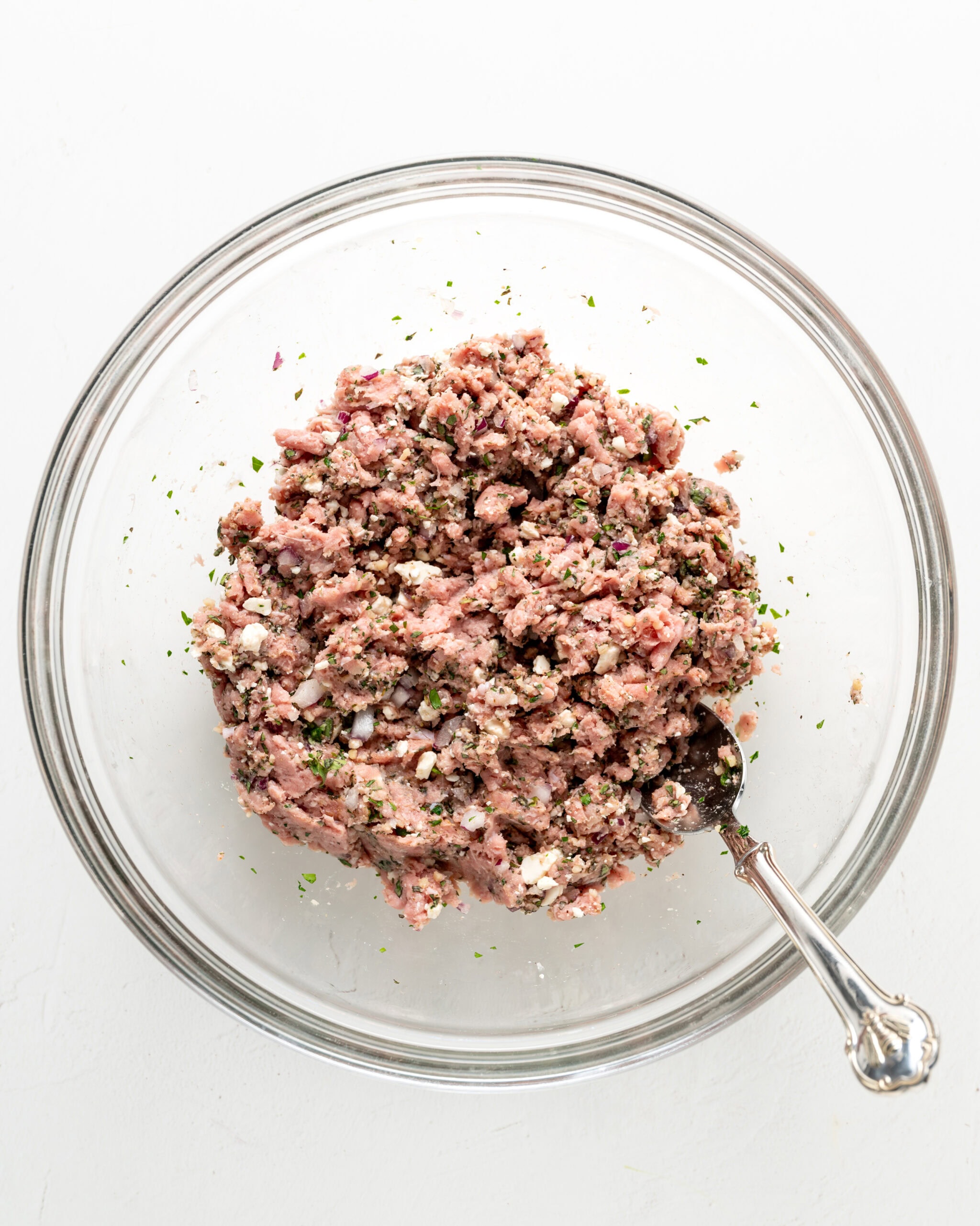 Mixing together mediterranean turkey burgers in a large bowl.