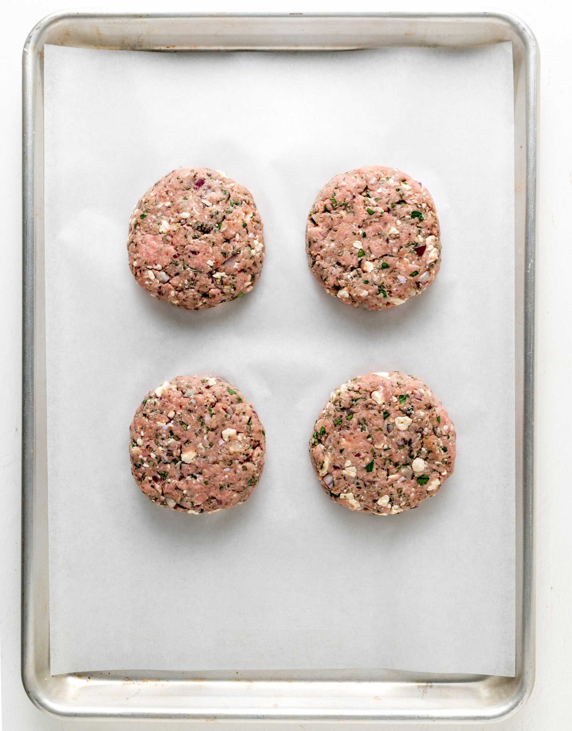 Turkey burgers on a lined baking sheet.