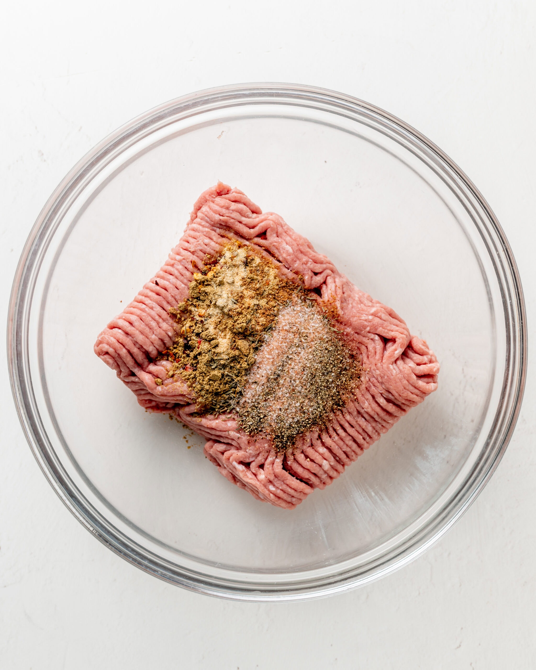Turkey in a large clear bowl with spices.
