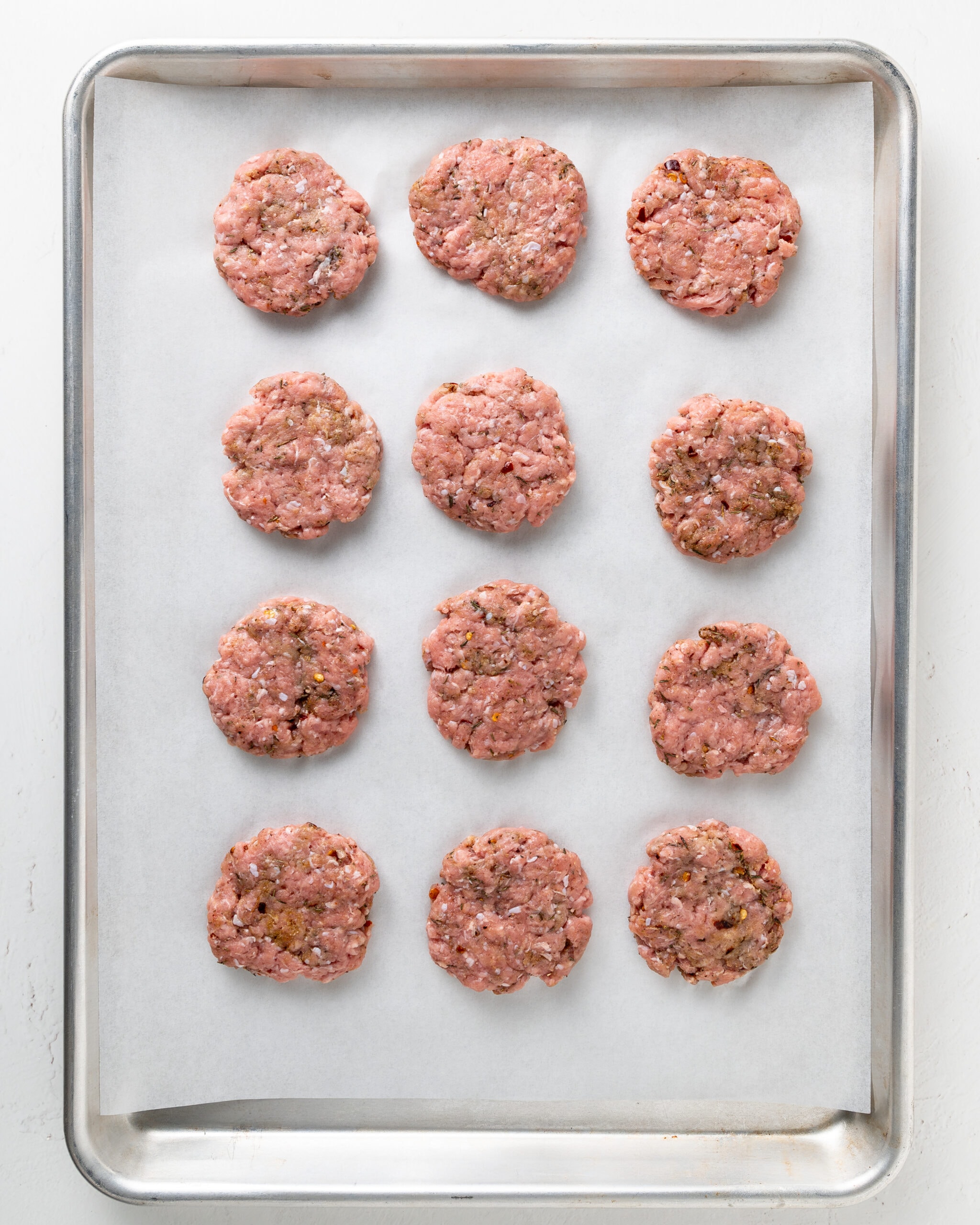 12 formed turkey breakfast patties on a parchment lined baking sheet.