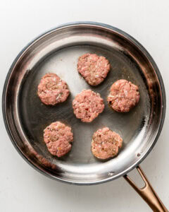 Frying turkey breakfast sausage in a large stainless steel pan.