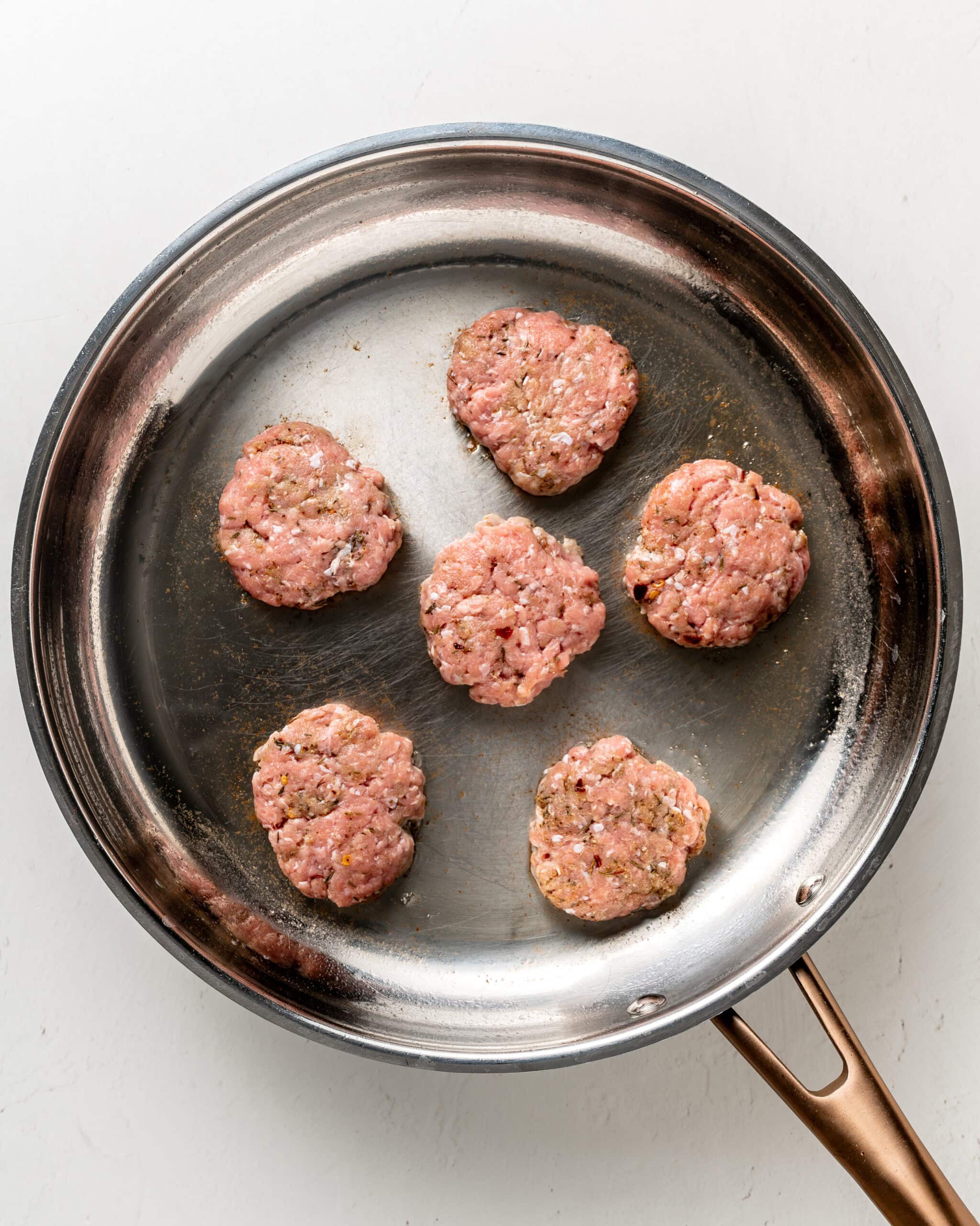 Six patties in a large stainless steel skillet.