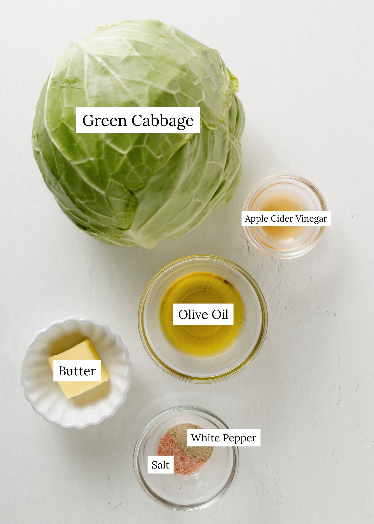 Ingredients for sauteed cabbage. Cabbage, apple cider vinegar, olive oil, butter, salt, white pepper.
