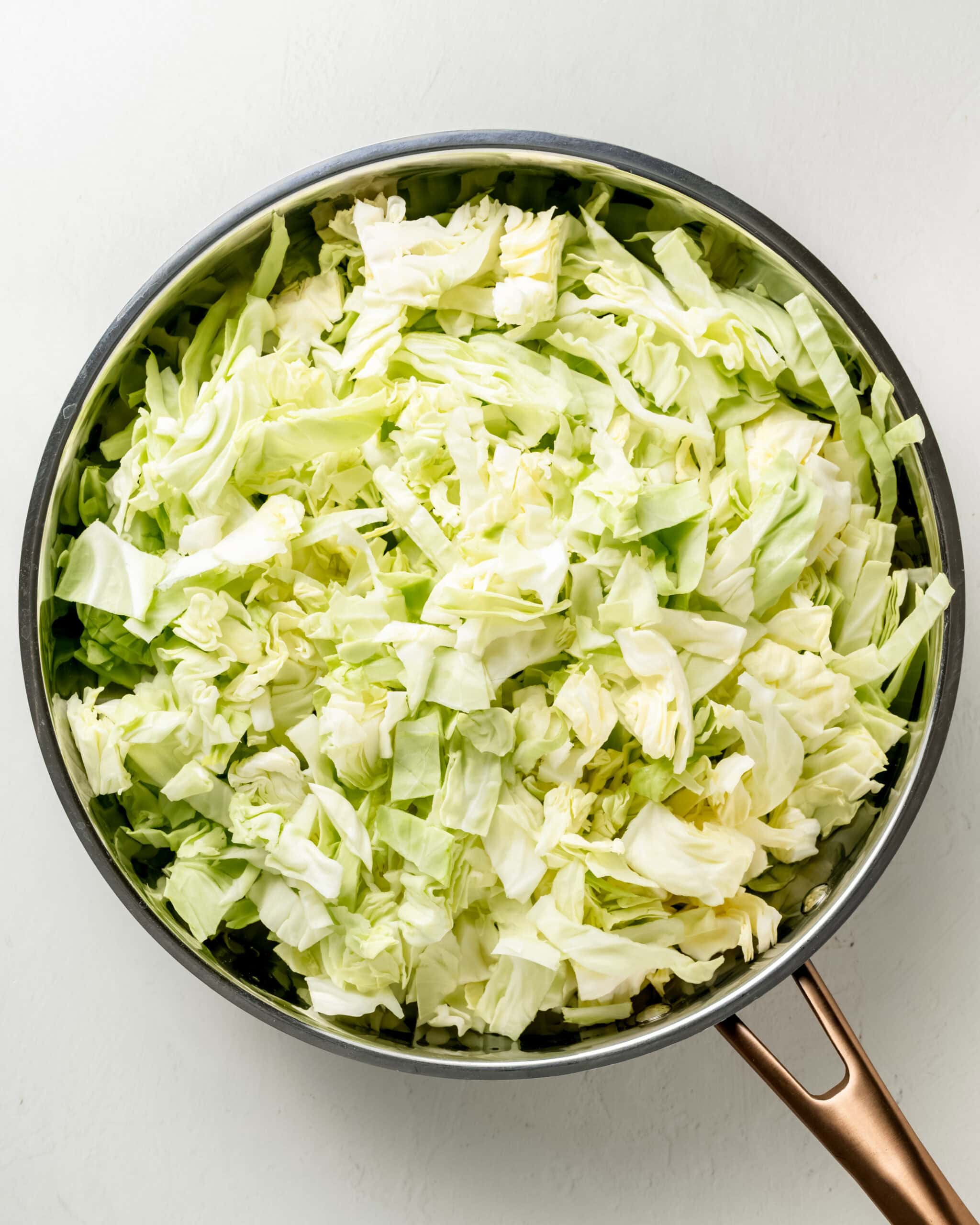 Add the green cabbage to a large skillet and saute.