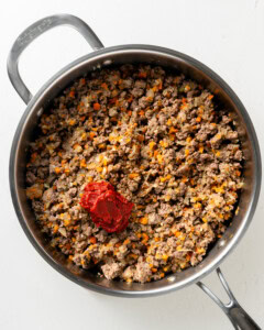 Adding tomato paste to lamb mixture.
