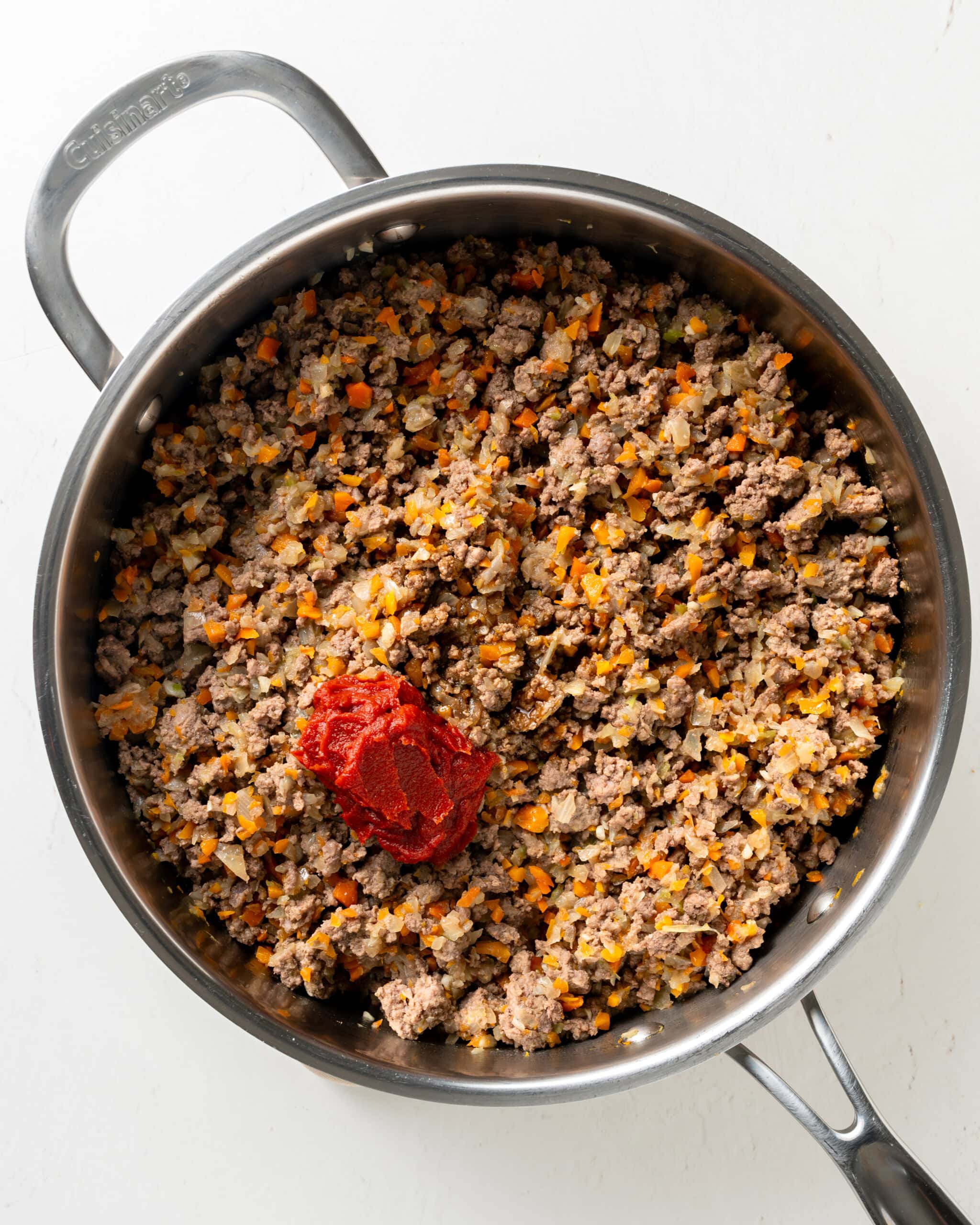 Adding tomato paste to lamb mixture.